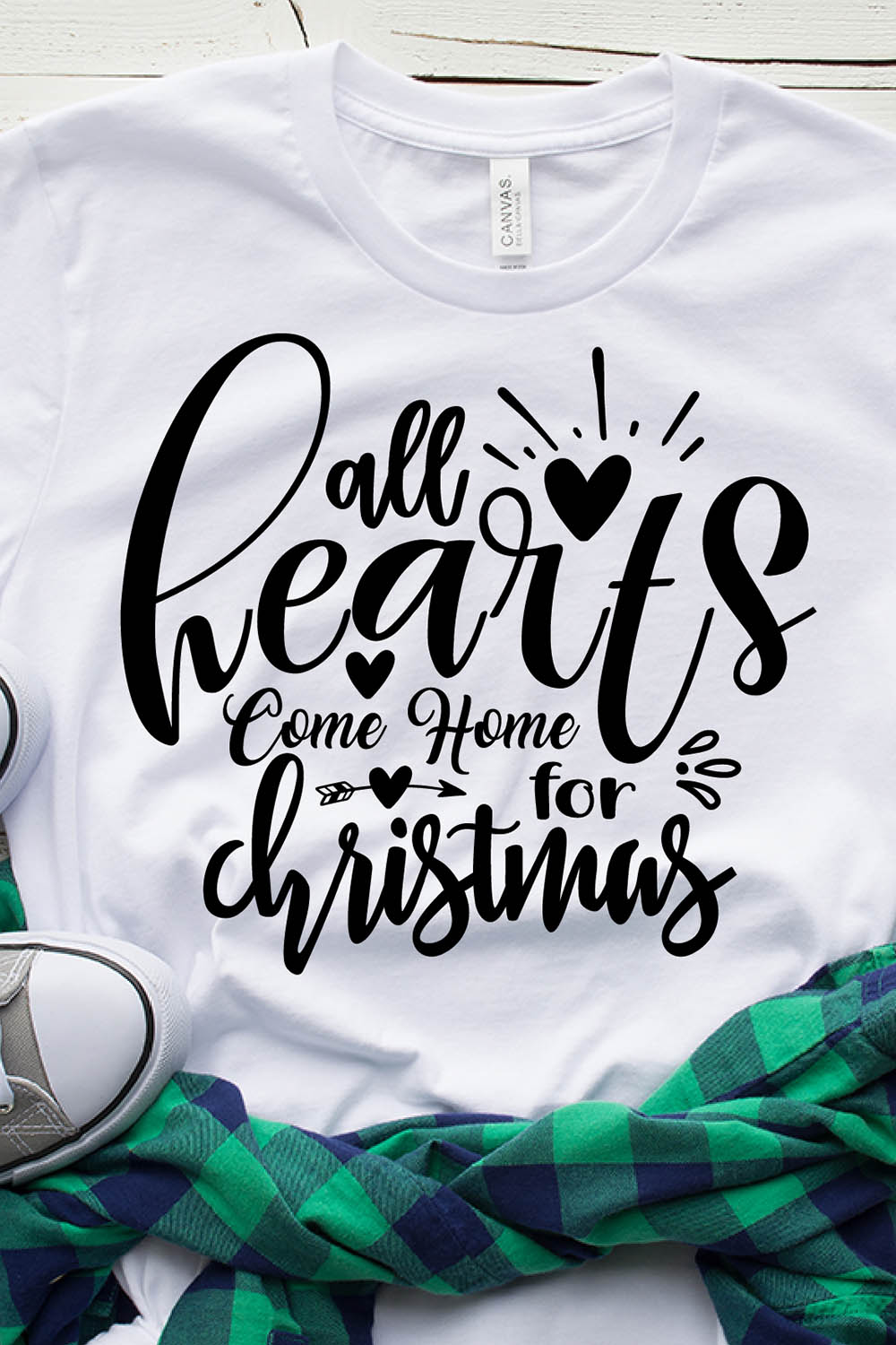 Image of a white t-shirt with a charming black slogan All Hearts Come Home For Christmas.