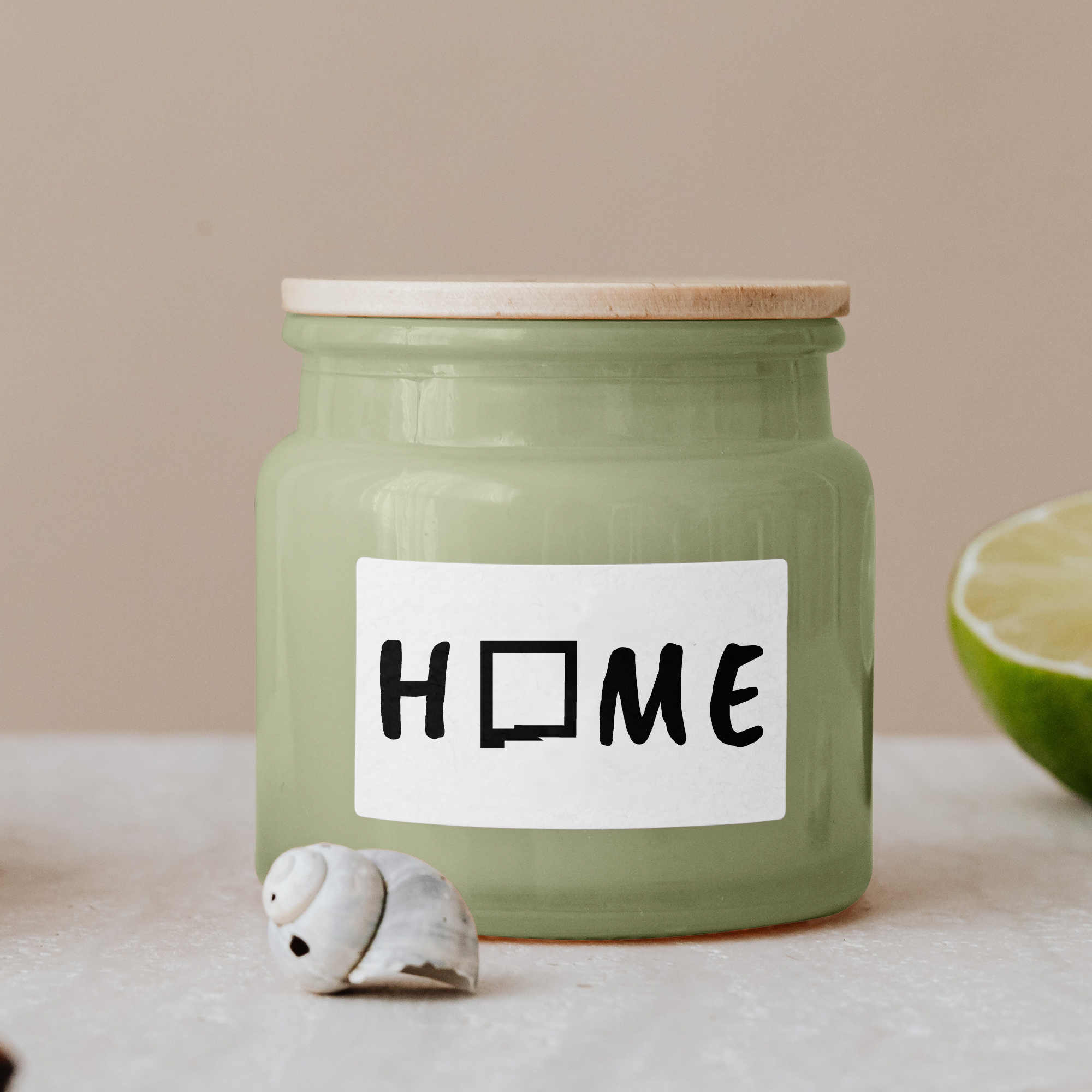 Black lettering "Home" on a white label on a green glass jar with wooden lid.