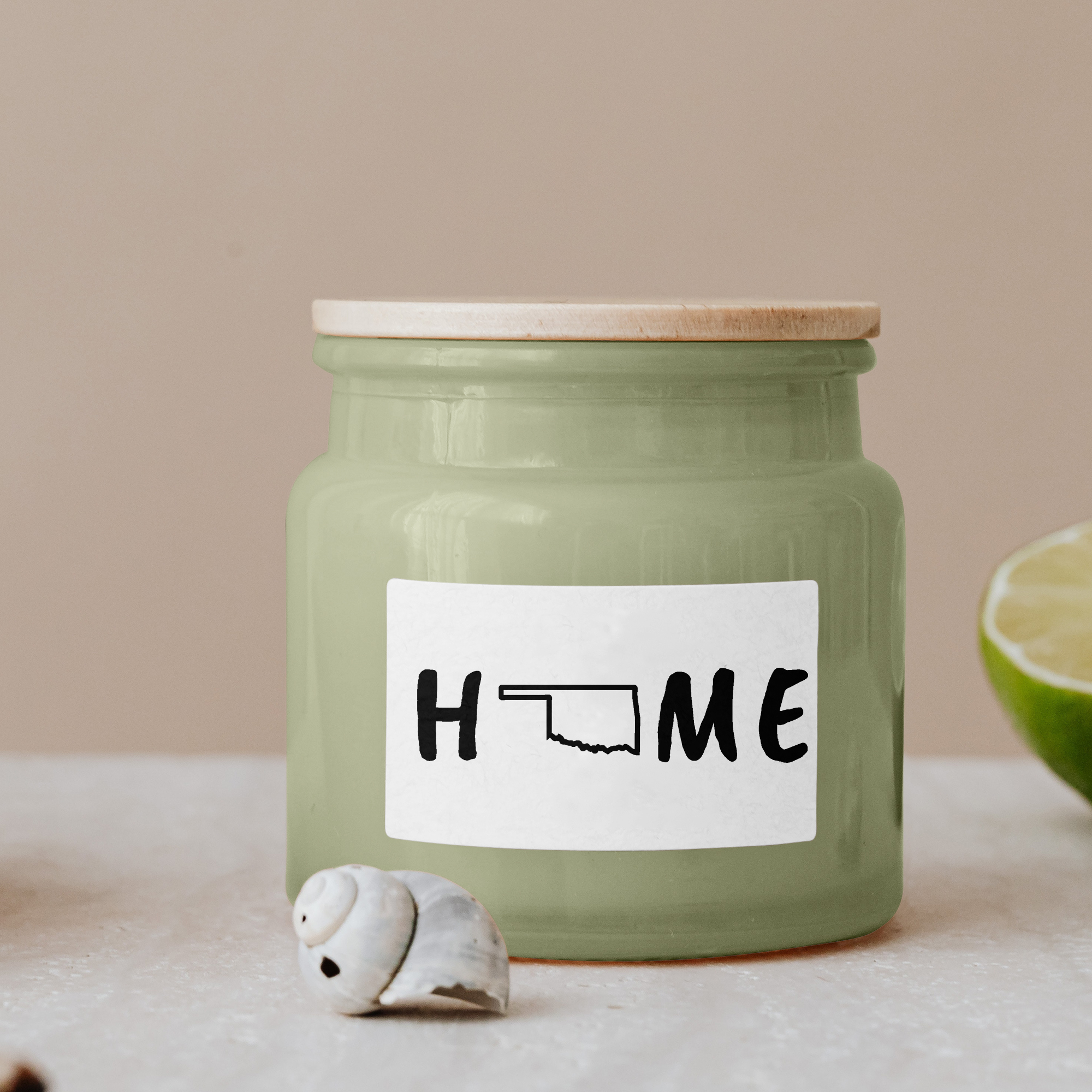 Black lettering "Home" on a white label on a green glass jar with wooden lid.