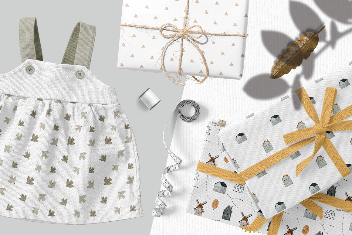 White baby dress and different white wrapping papers with patterns of a bird and houses.