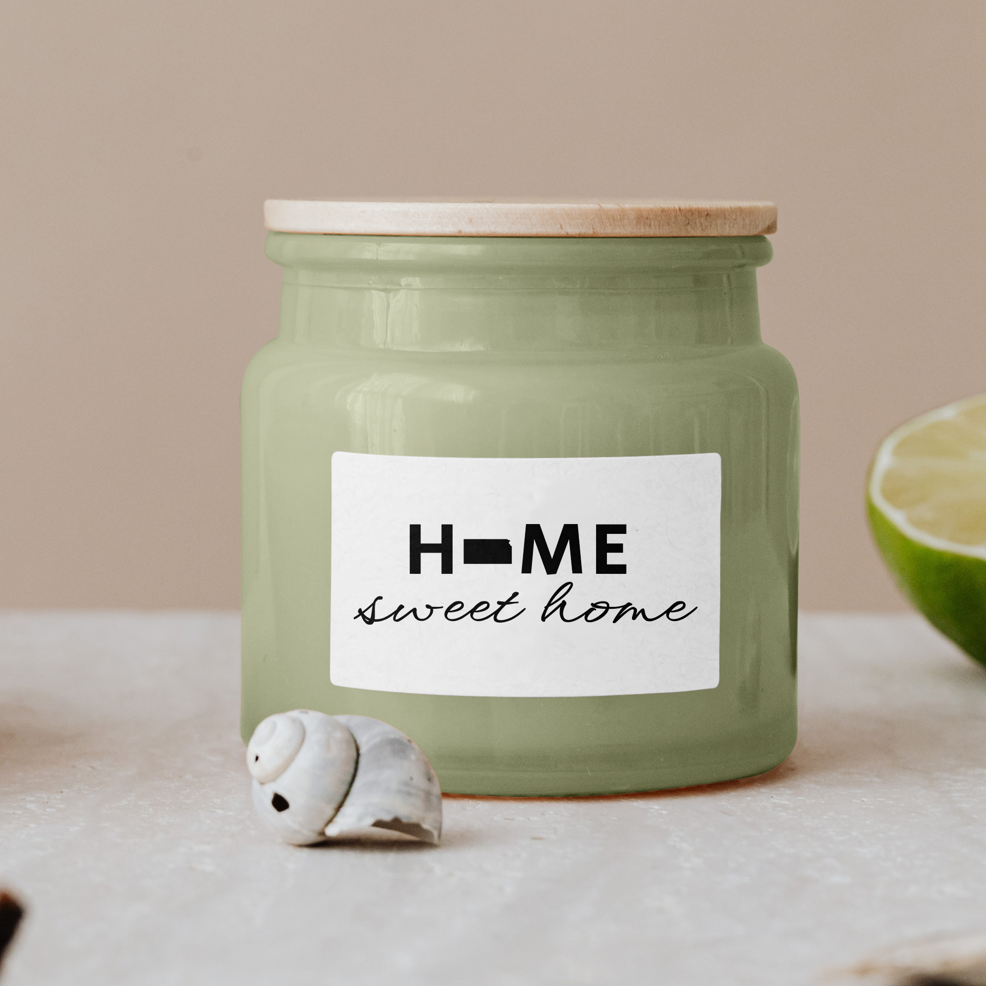 Black lettering "Home sweet home" on a white label on a green glass jar with wooden lid.