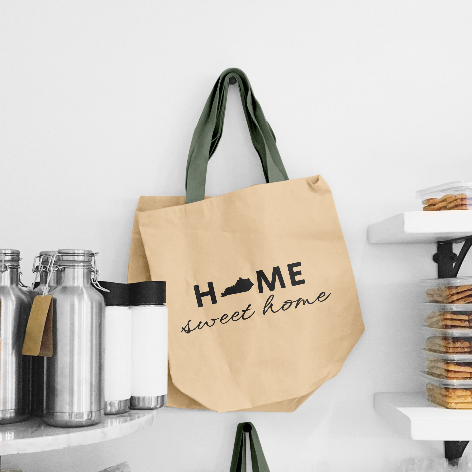Black lettering "Home sweet home" on the beige shopping bag with dirty green handle.