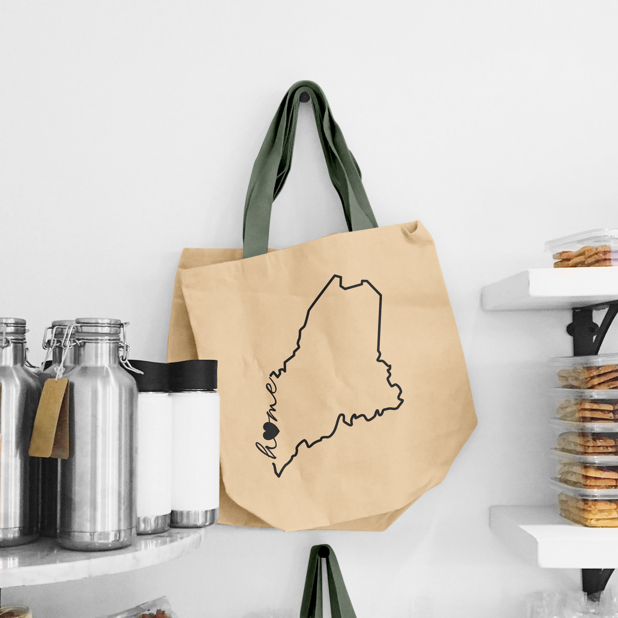 Black illustration of map of Maine on the beige shopping bag with dirty green handle.
