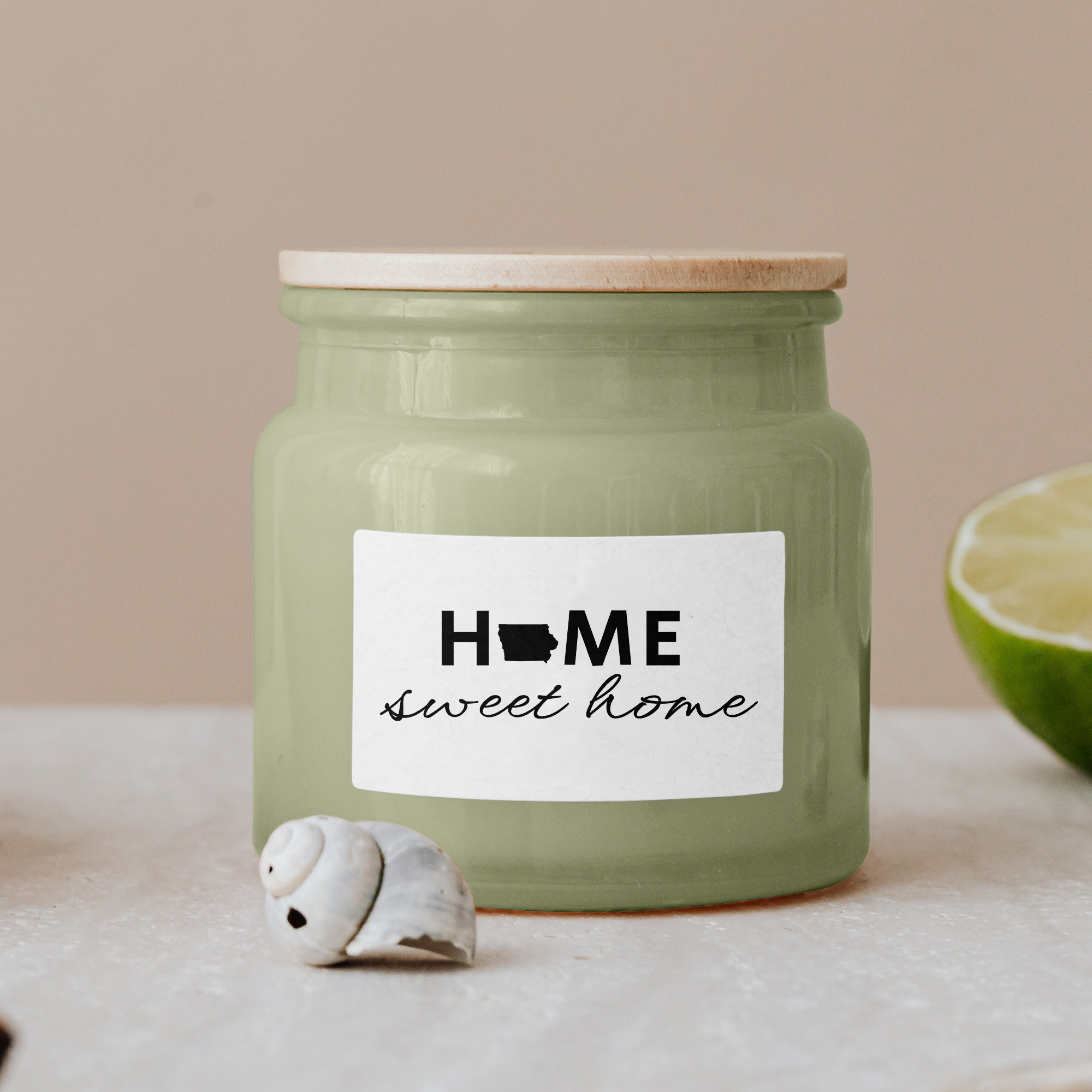 Black lettering "Home sweet home" on a white label on a green glass jar with wooden lid.