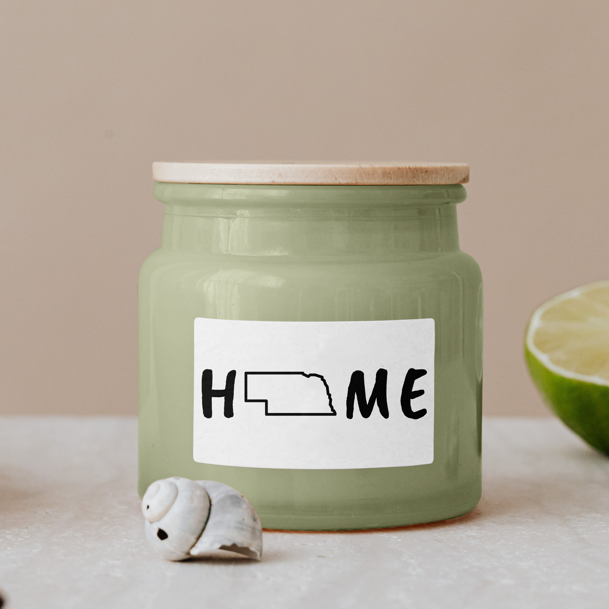 Black lettering "Home" on a white label on a green glass jar with wooden lid.