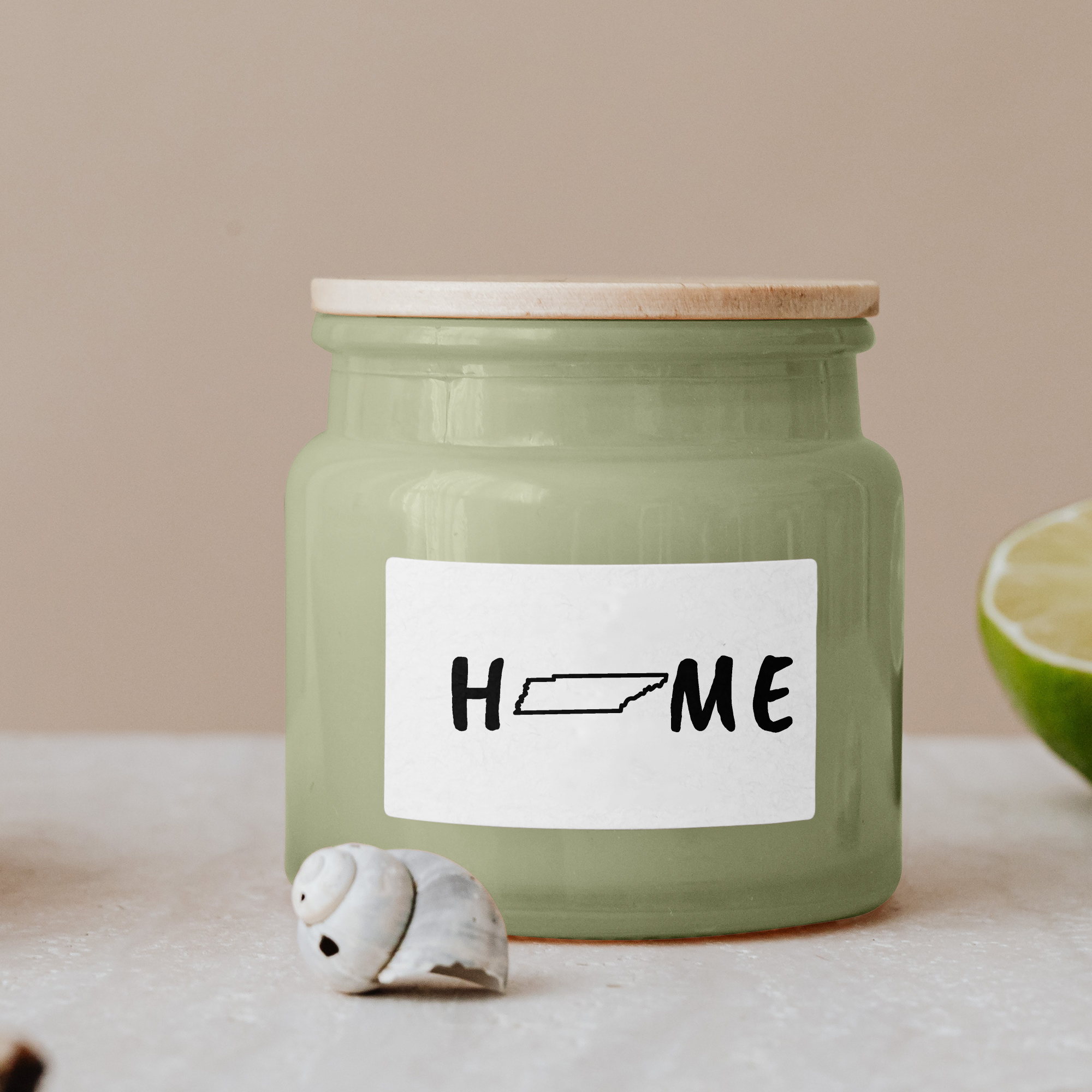 Black lettering "Home" on a white label on a green glass jar with wooden lid.