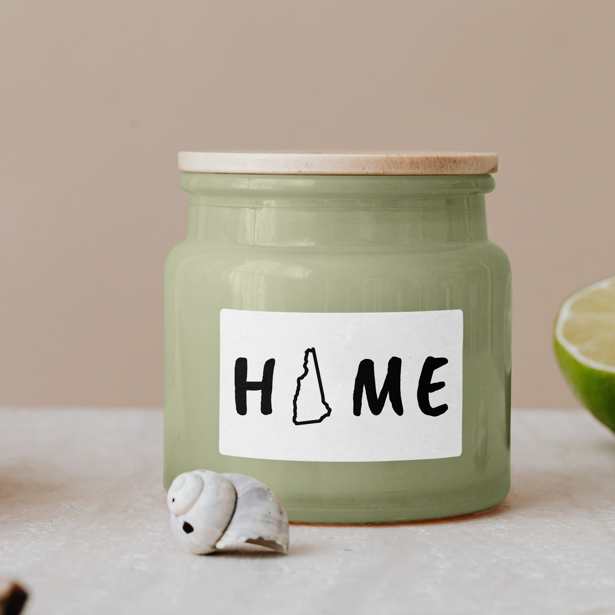 Black lettering "Home" on a white label on a green glass jar with wooden lid.