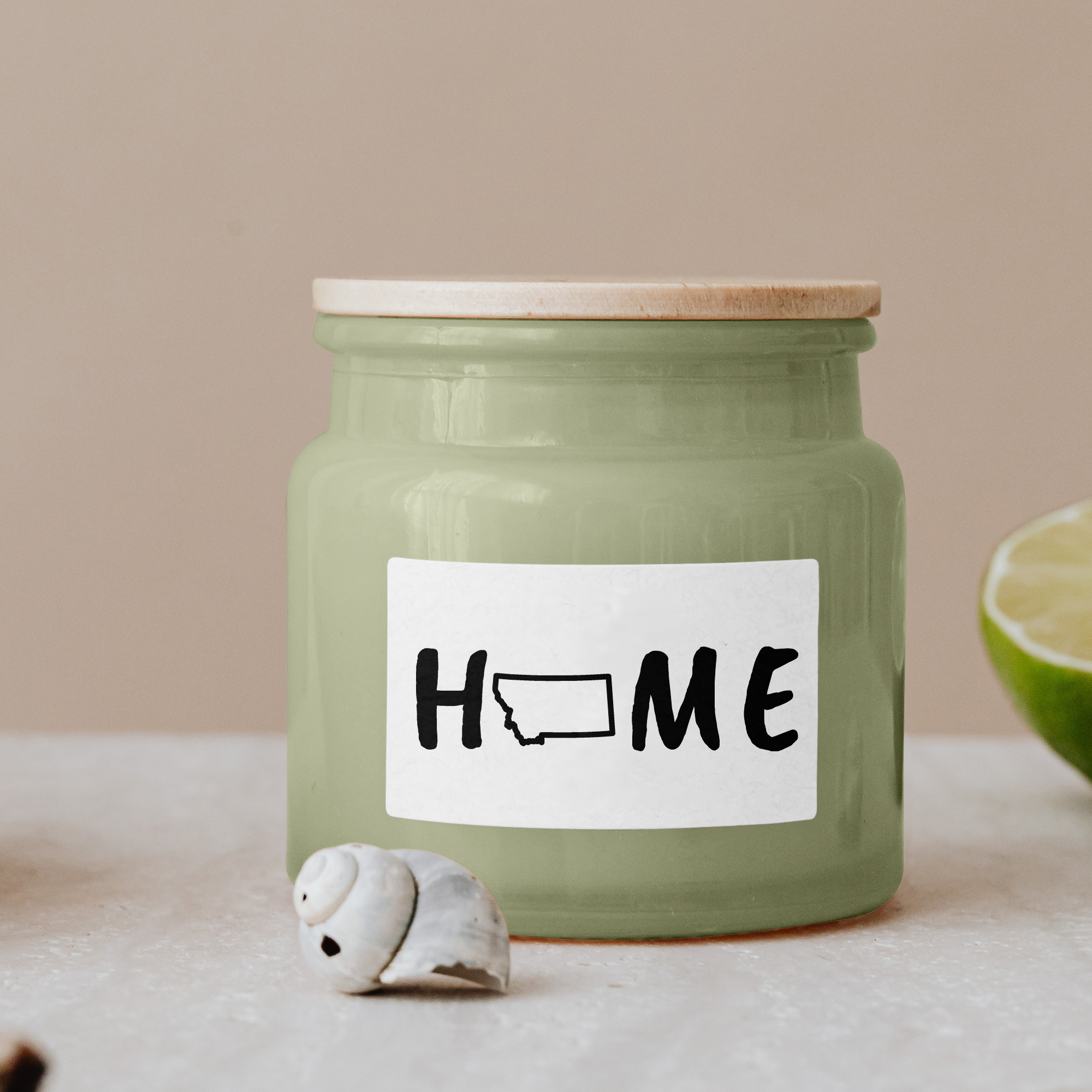 Black lettering "Home" on a white label on a green glass jar with wooden lid.