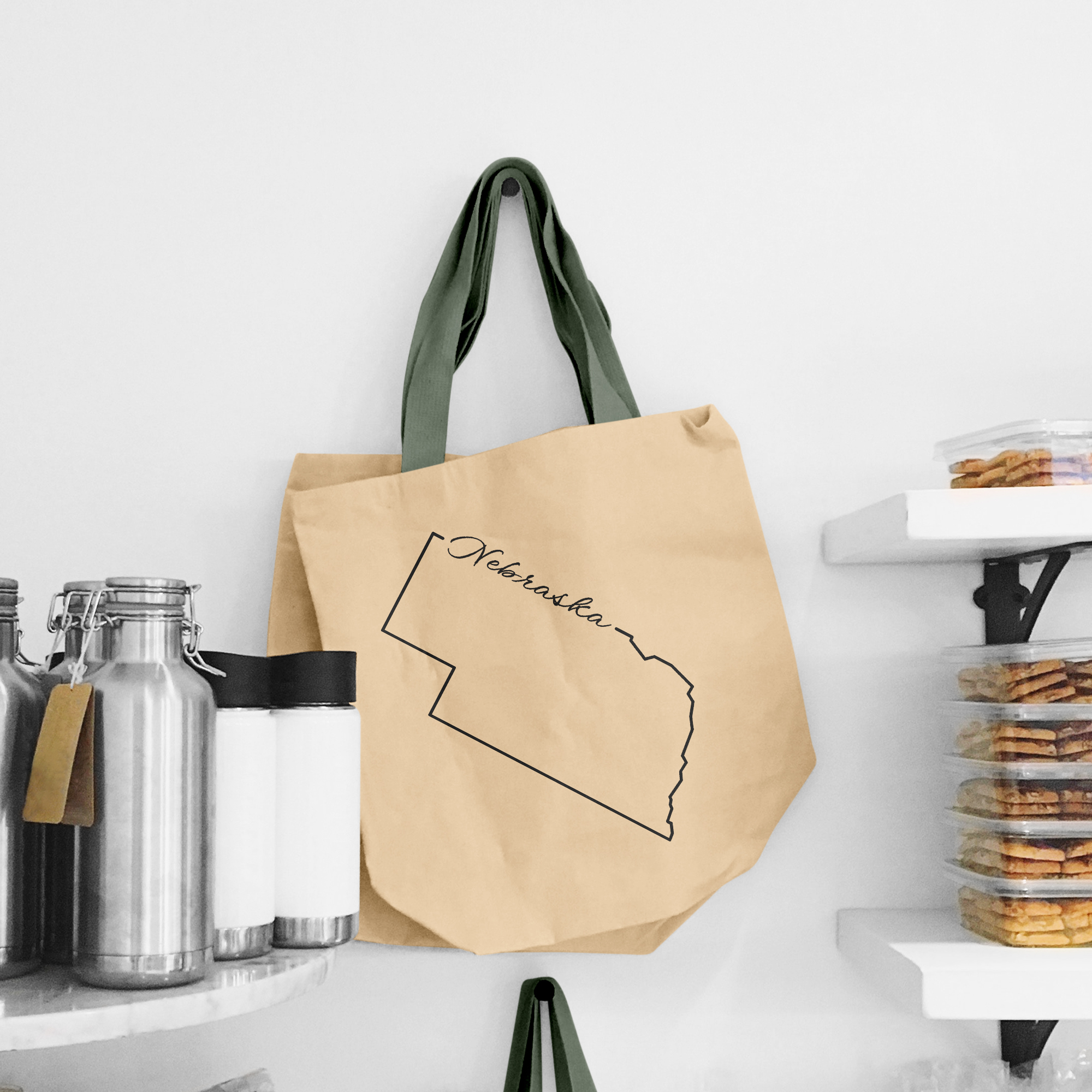 Black illustration of map of Nebraska on the beige shopping bag with dirty green handle.