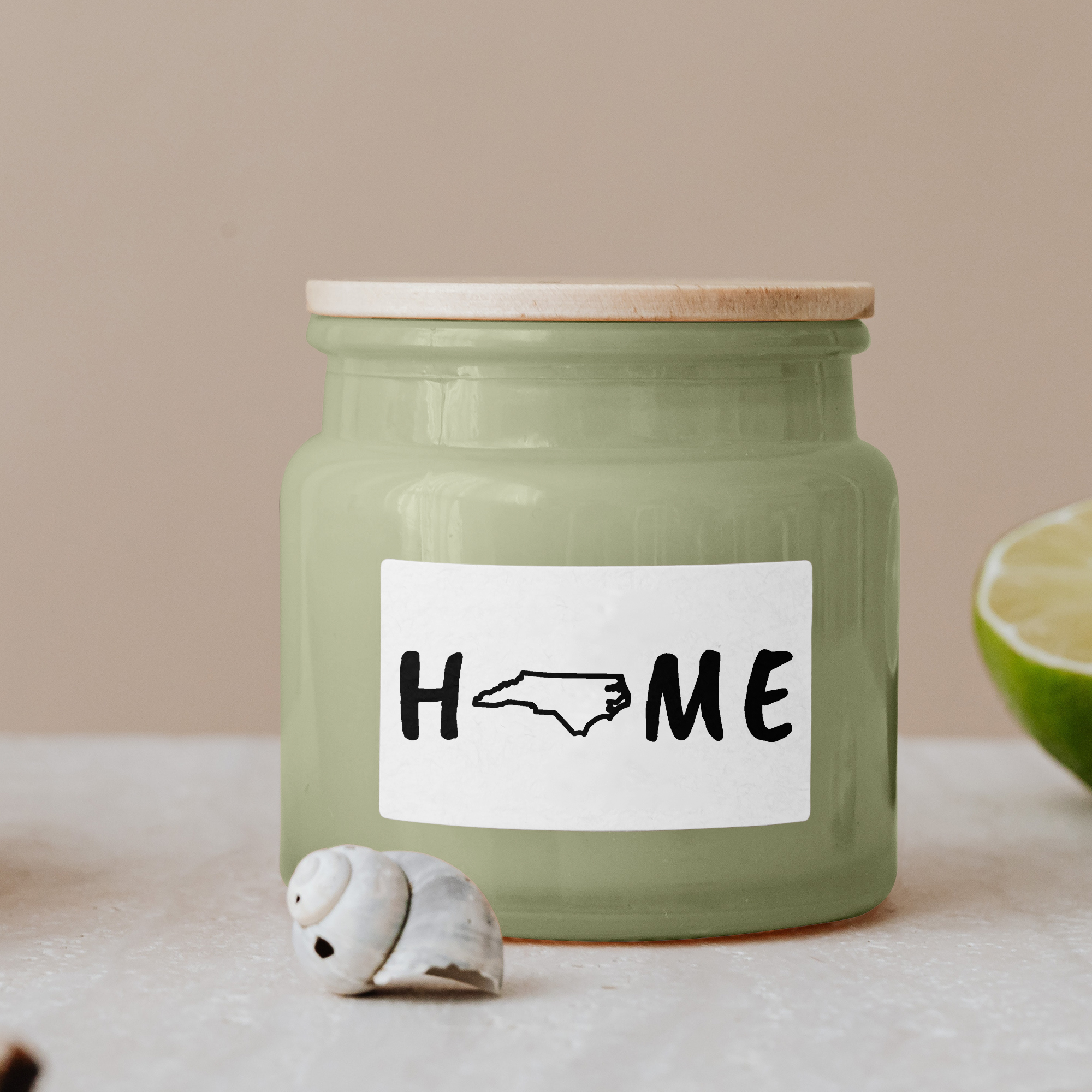 Black lettering "Home" on a white label on a green glass jar with wooden lid.