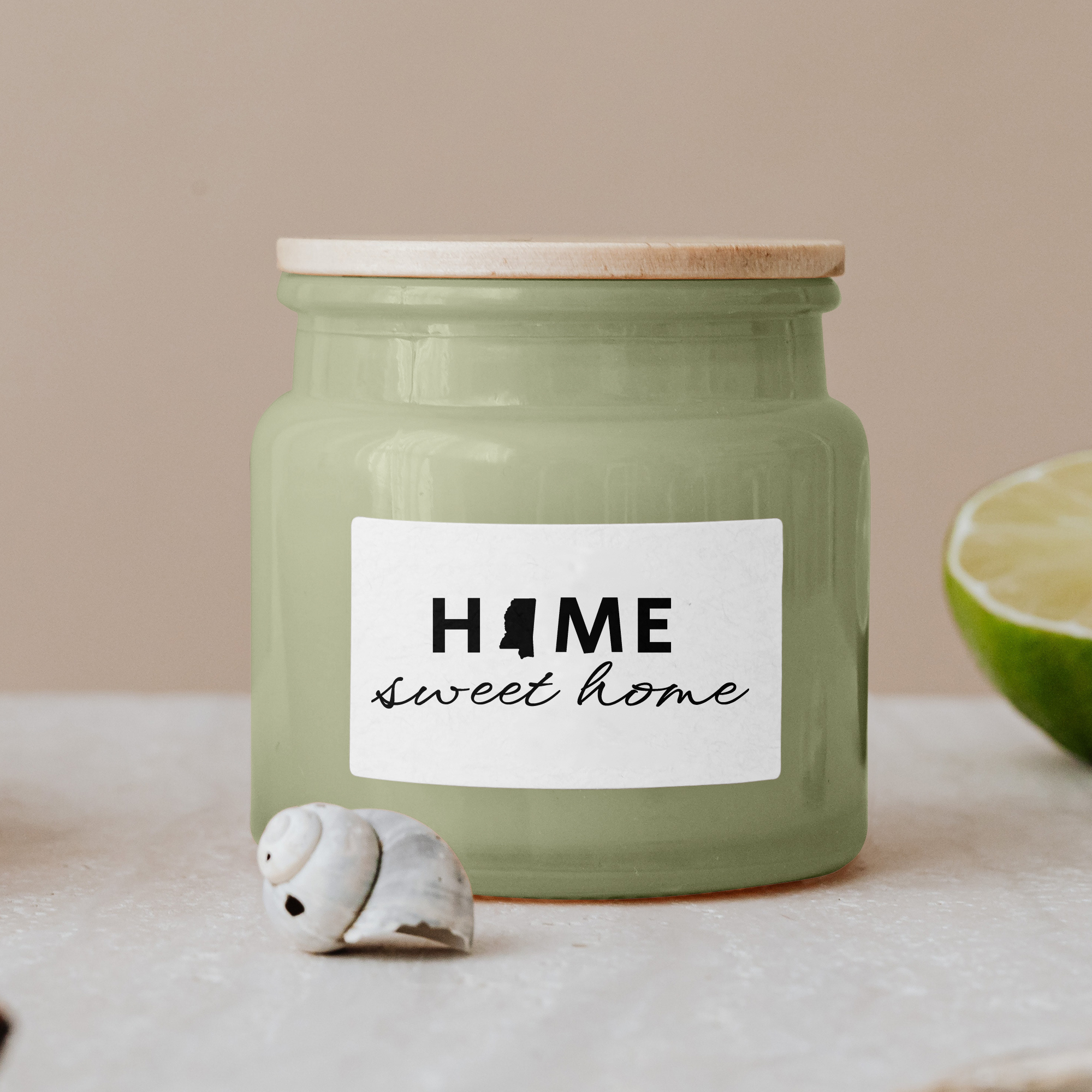 Black lettering "Home sweet home" on a white label on a green glass jar with wooden lid.