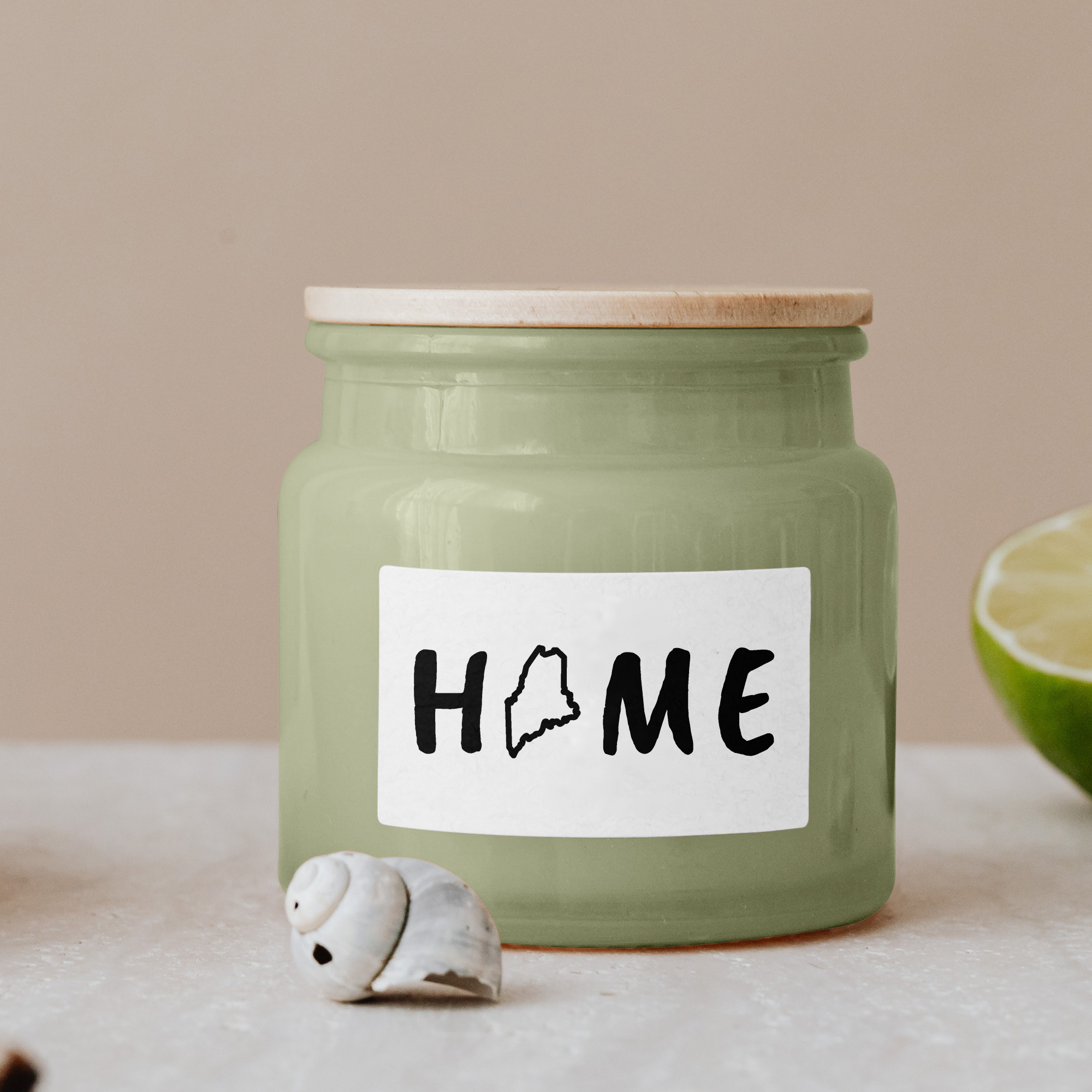 Black lettering "Home" on a white label on a green glass jar with wooden lid.