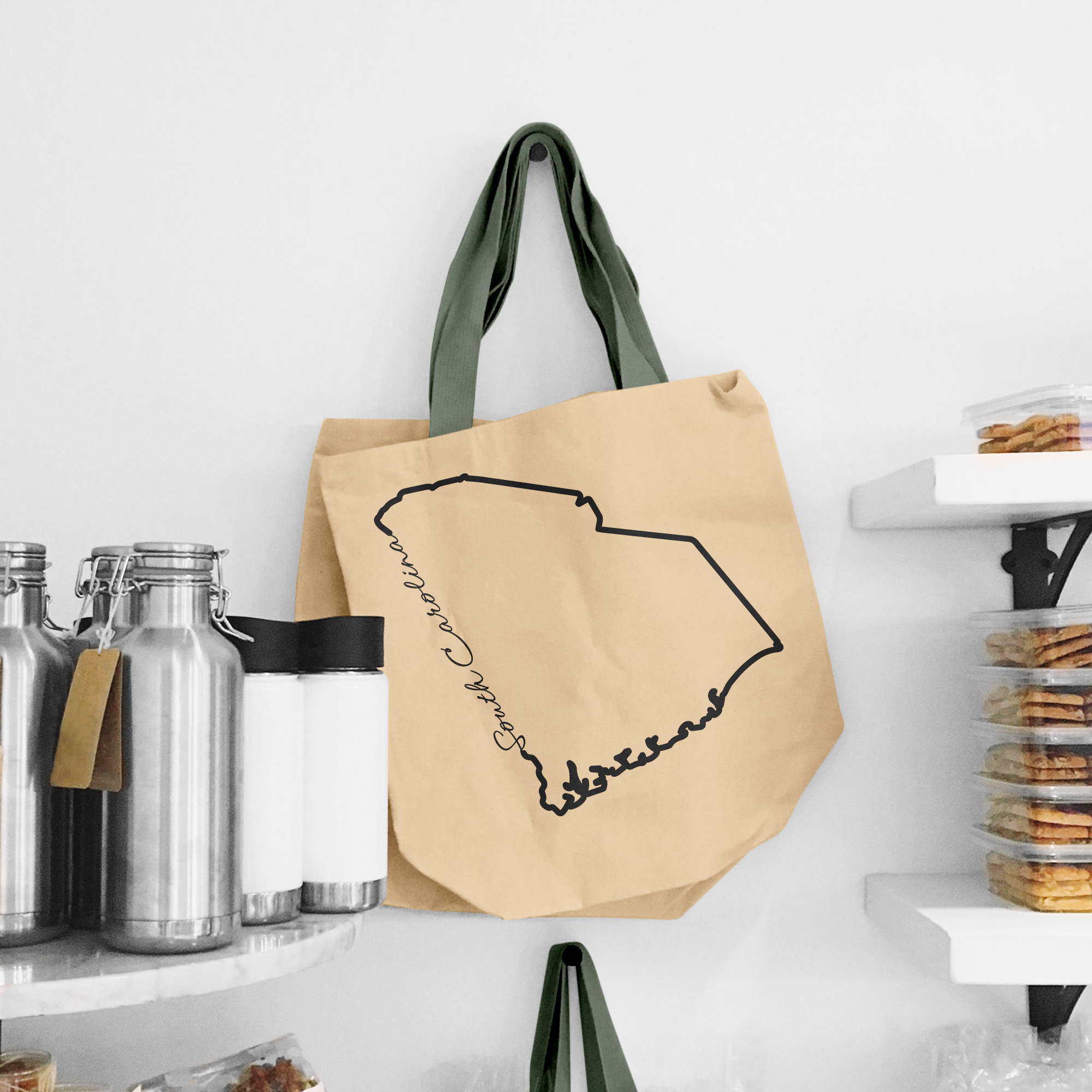 Black illustration of map of South Carolina on the beige shopping bag with dirty green handle.