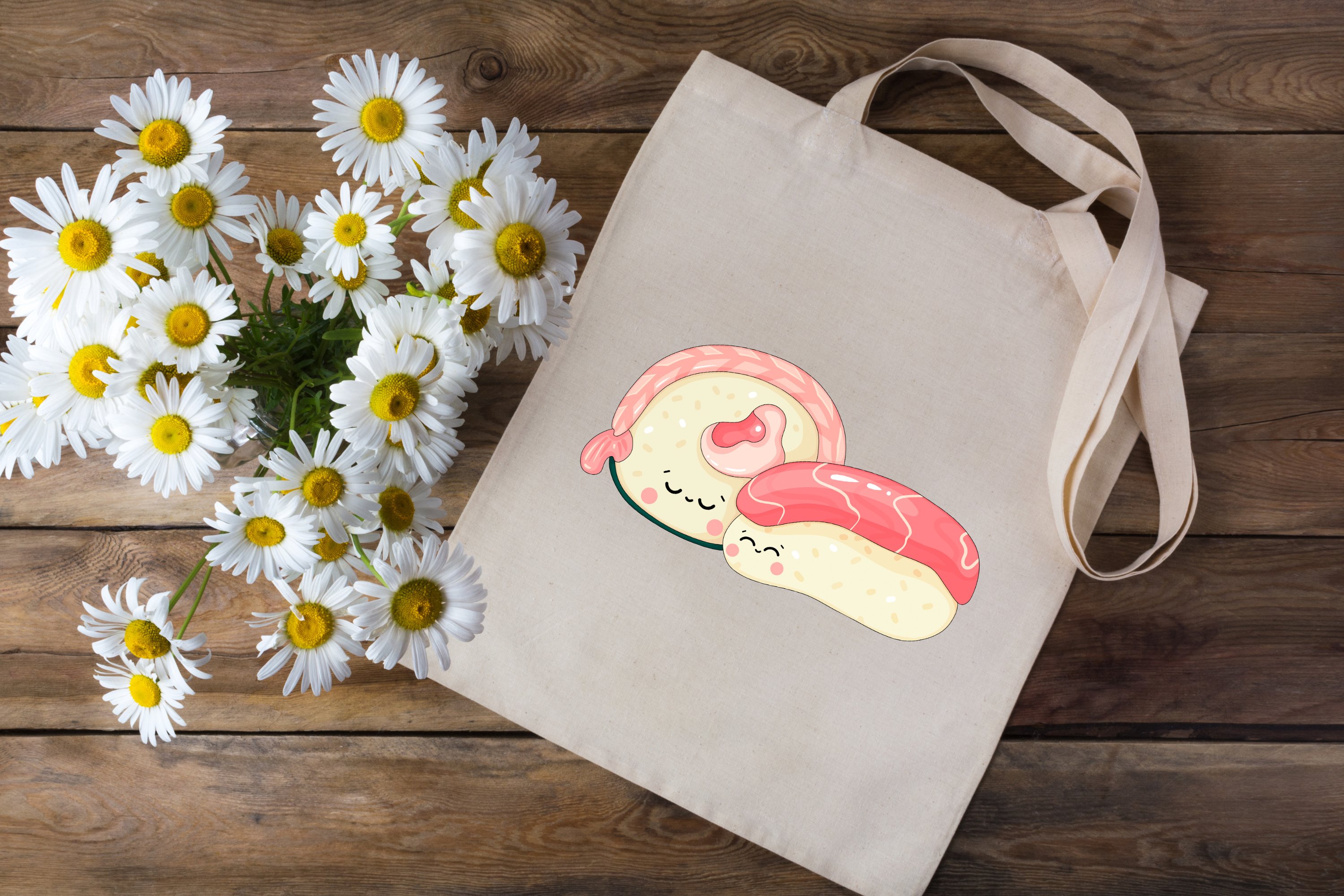 Beige shopping bag with cute sushi printable on the wooden background with chamomile.