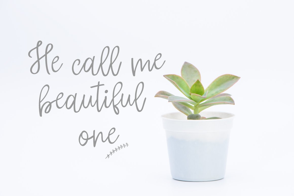 Gray lettering "He call me beautiful one" in script font and plant in pot.