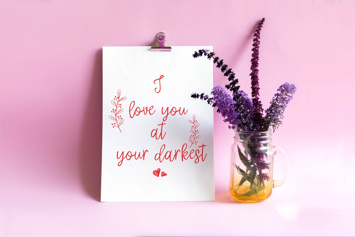 White card with red script lettering and lavender in cup on a pink background.