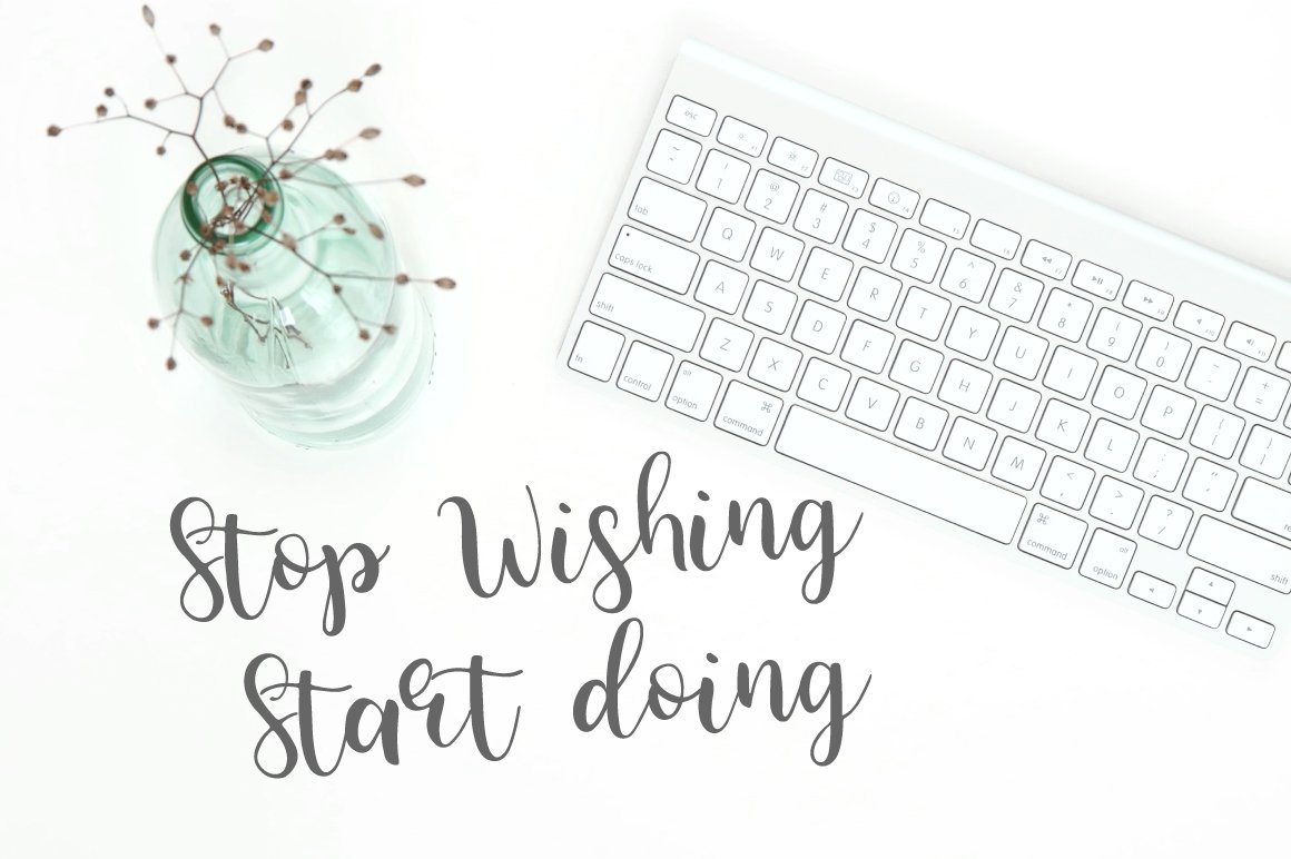 Gray lettering "Stop wishing start doing" on the white background with vase and keyboard.