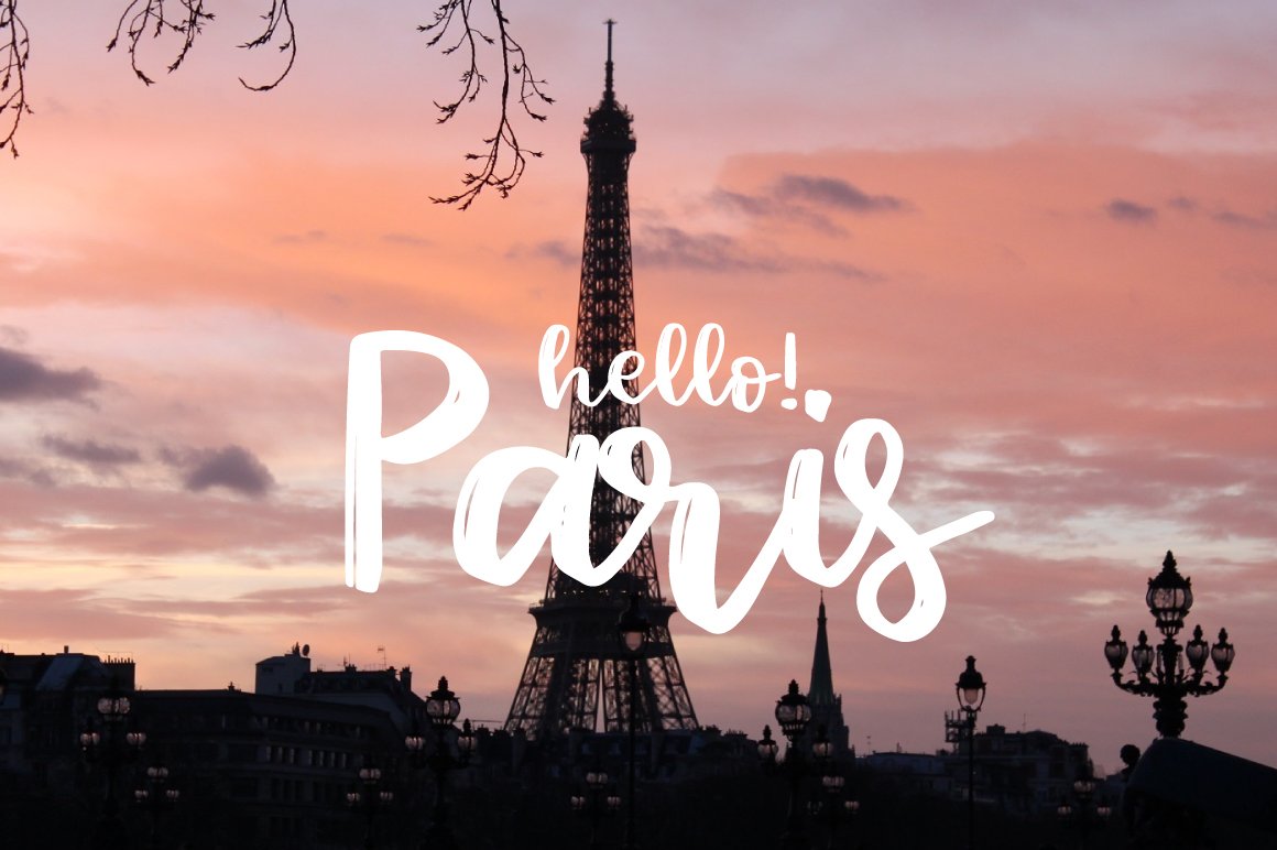 White lettering "Hello! Paris" in barbala handwritten font on the background of Paris.
