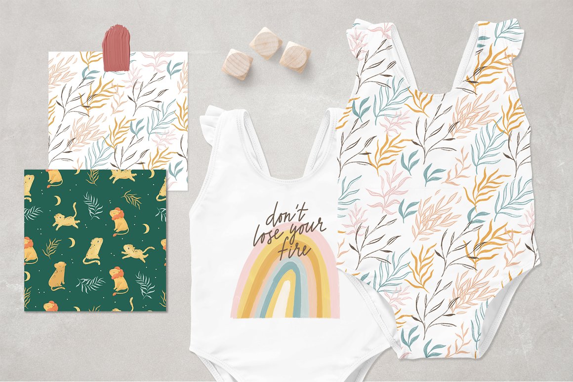 White and green patterns and white baby bodysuit with illustrations of rainbow and leaves.