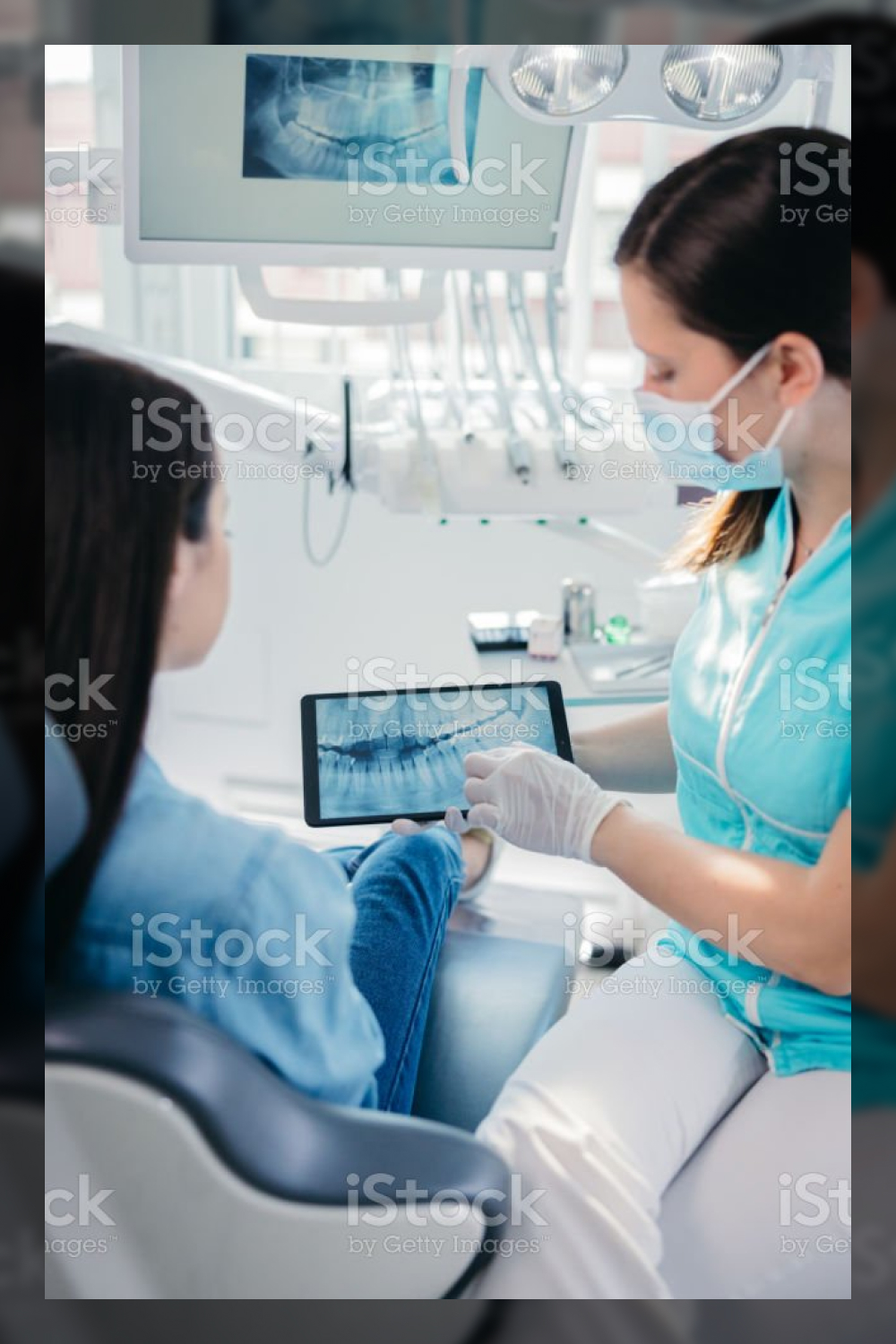 Female dentist showing dental x ray to female patient stock photo.