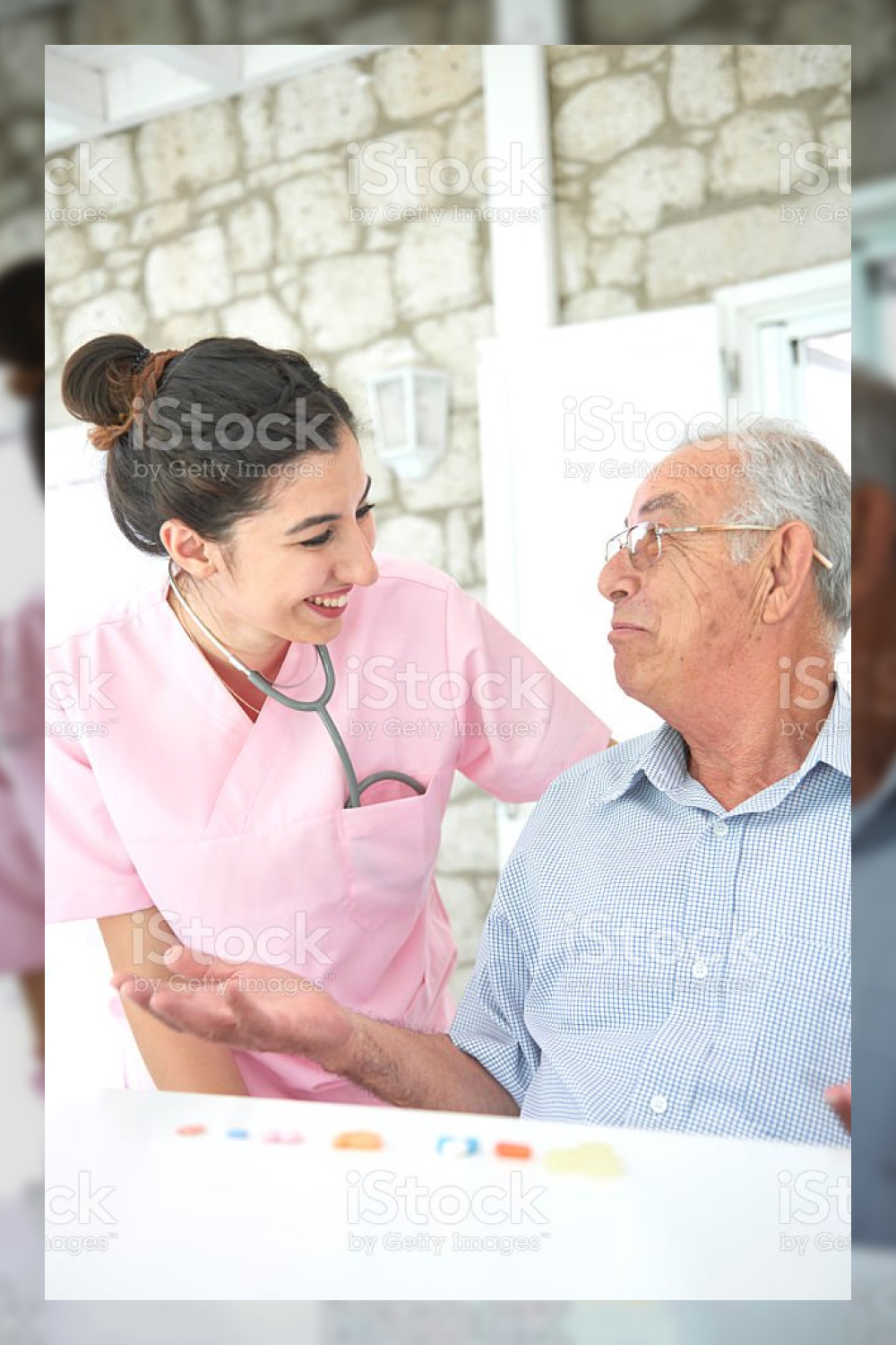 Nurse helping old man to arrange pills stock photo.