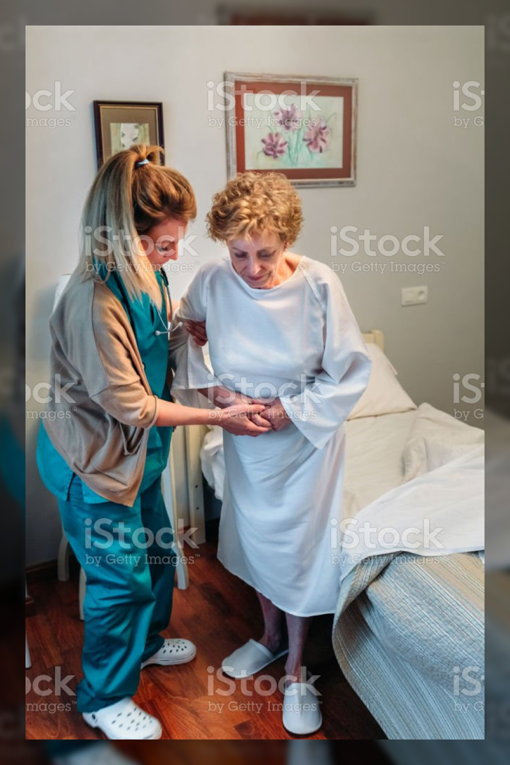 Caregiver helping elderly patient to stand up stock photo.