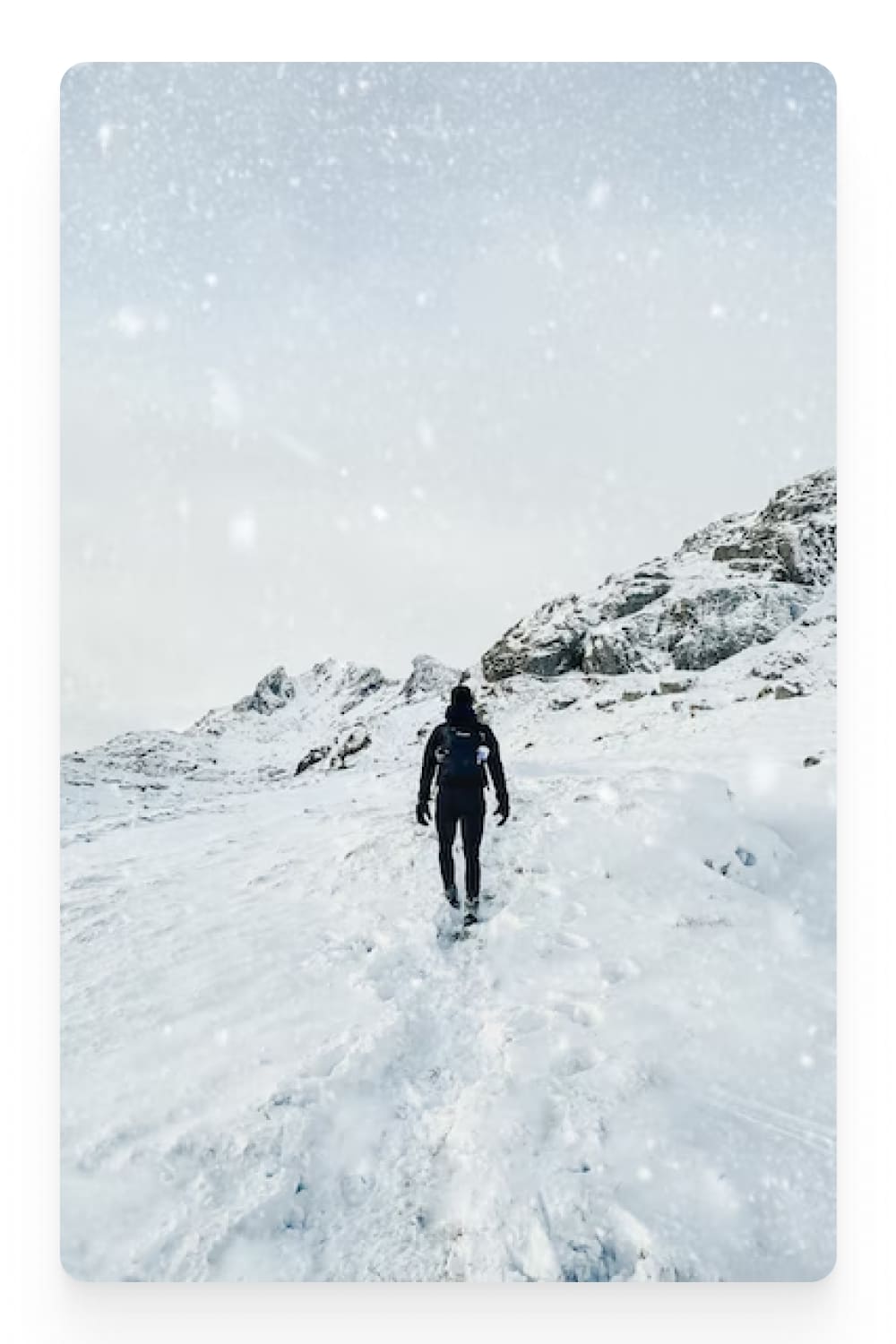 Photo of a hiker on a trail in the snowy mountains.