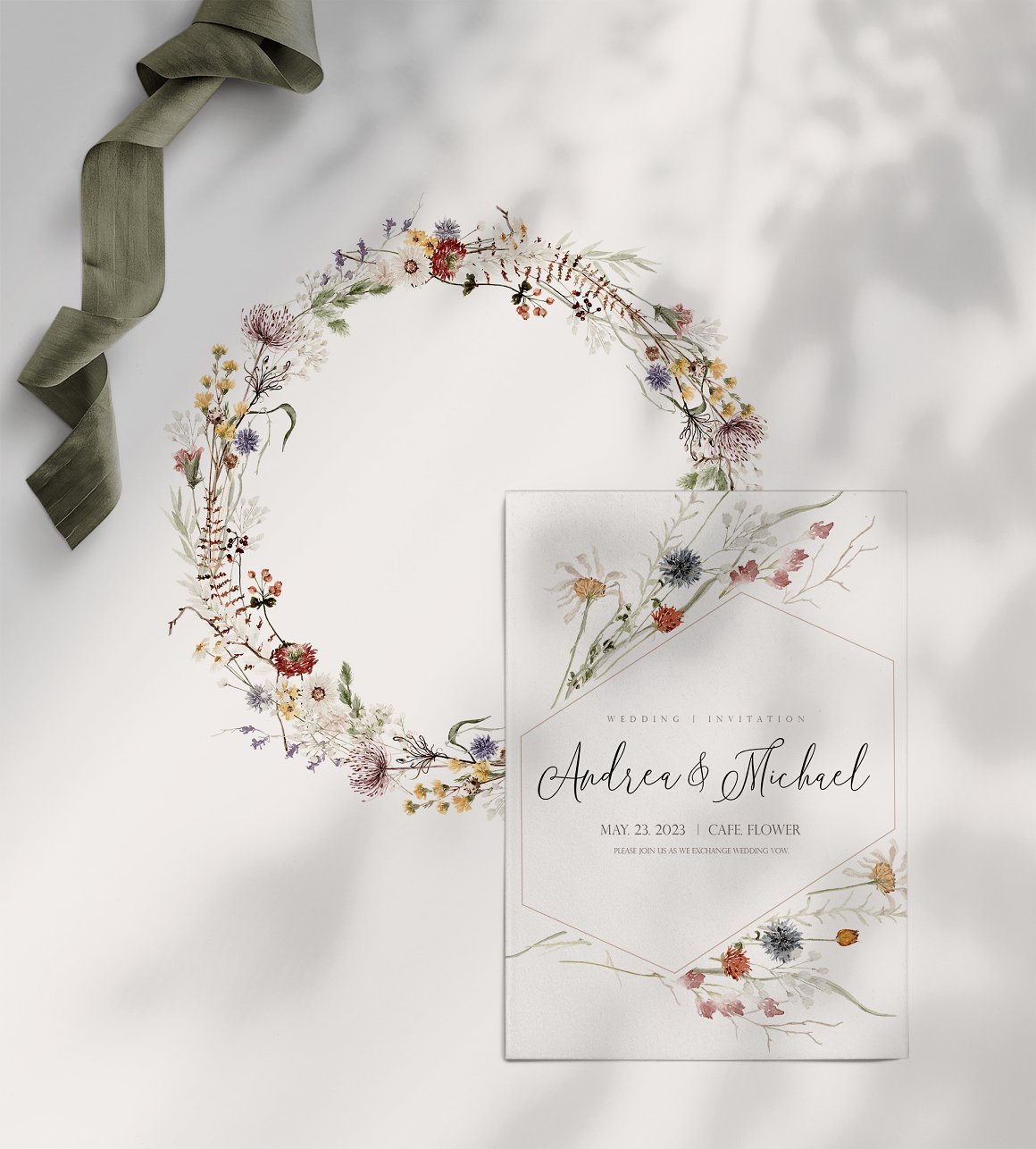 Floral wreath and white boho wedding card on a gray background.