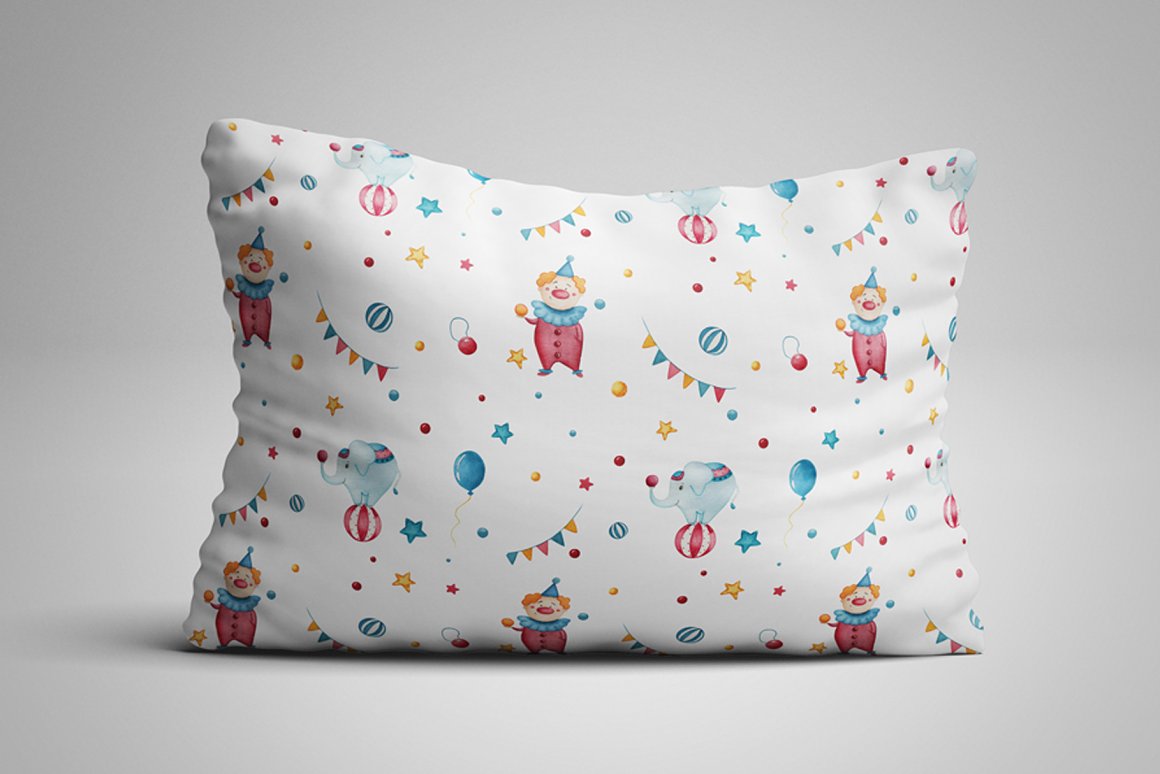 White pillow with patterns of clown and elephant on a gray background.