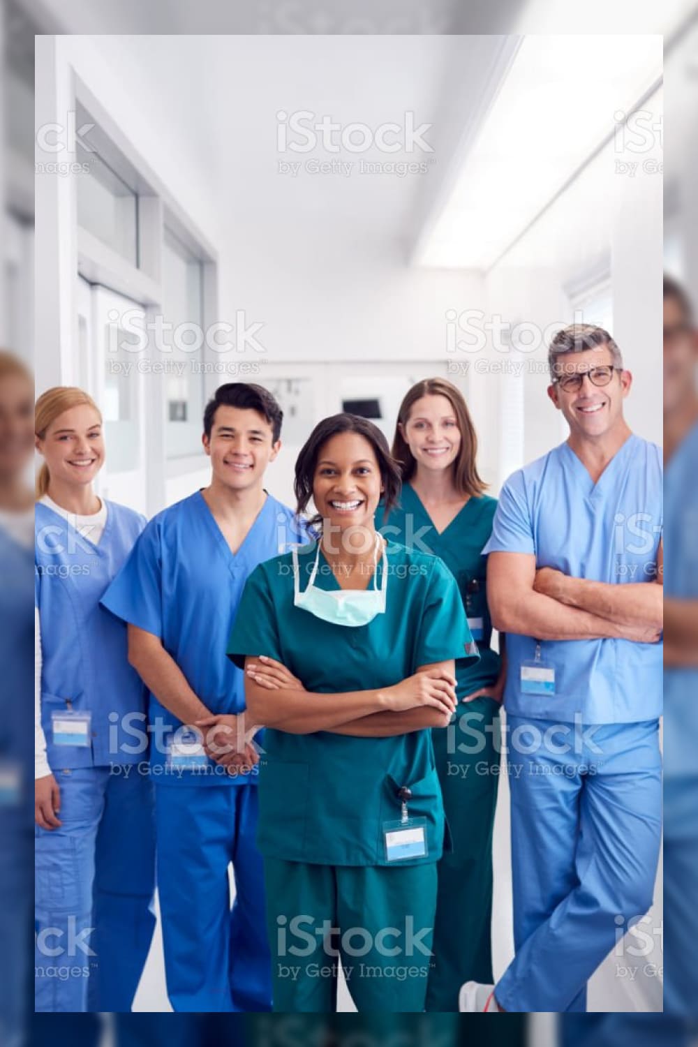 Portrait of smiling multi cultural medical team standing in hospital corridor stock photo.