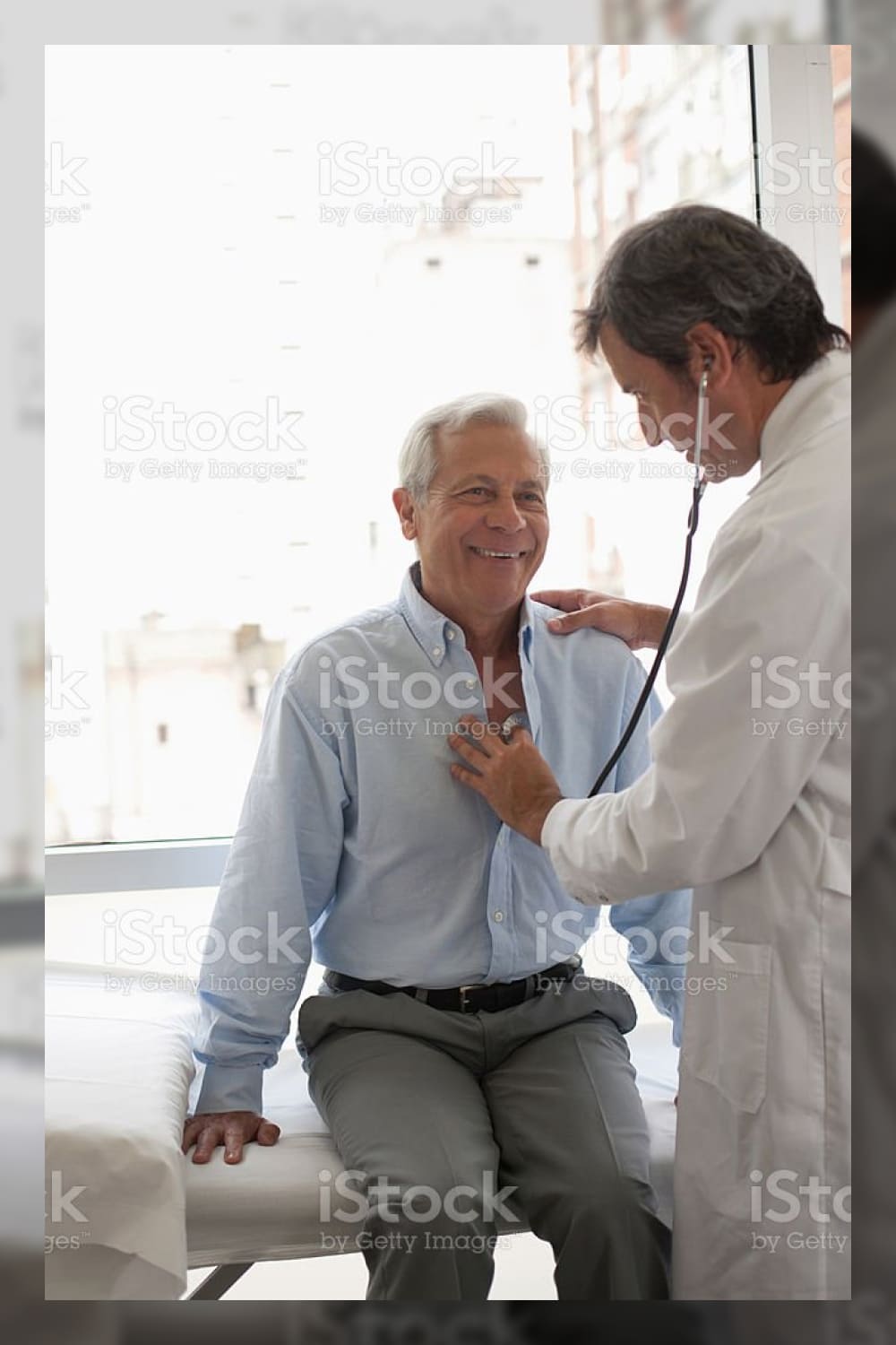 Doctor using stethoscope on smiling patient stock photo.