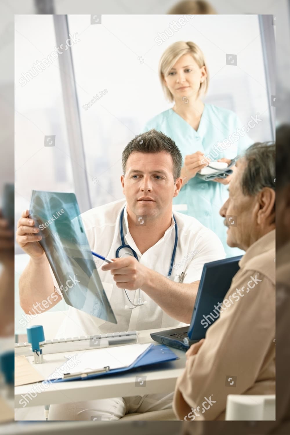 Doctor discussing diagnosis of x ray image with older patient sitting in office nurse in background.