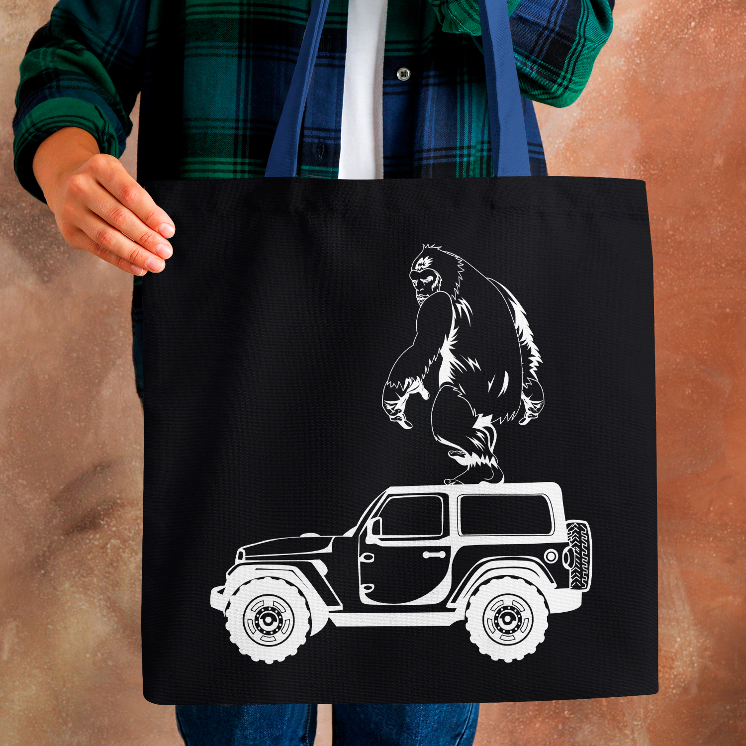 Person holding a black bag with a gorilla on top of a jeep.