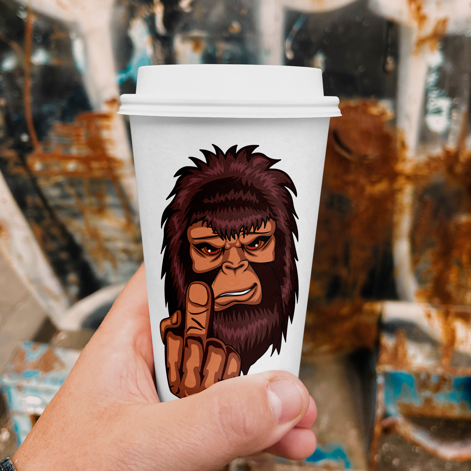 Hand holding a coffee cup with a picture of a gorilla on it.
