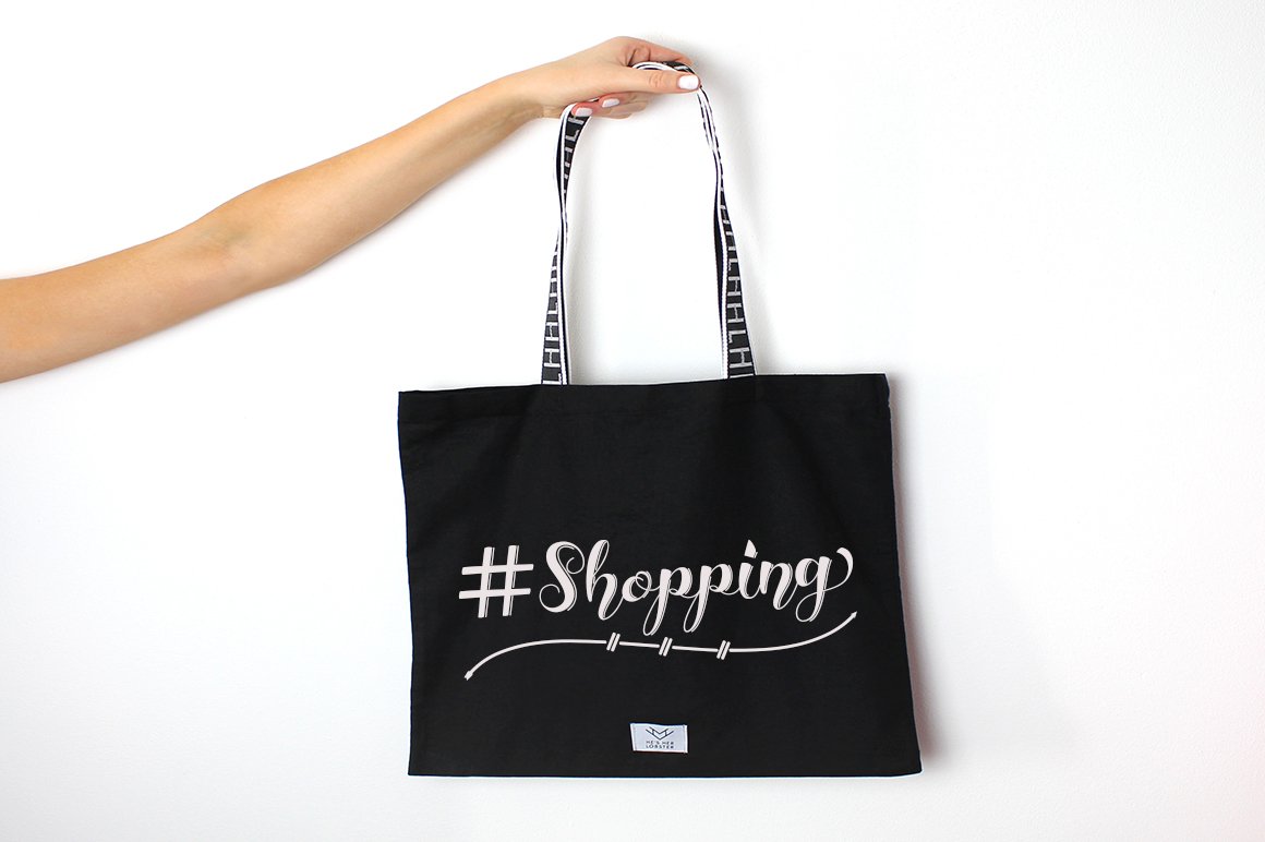 Black shopping bag with white calligraphy lettering "Shopping" on a white background.