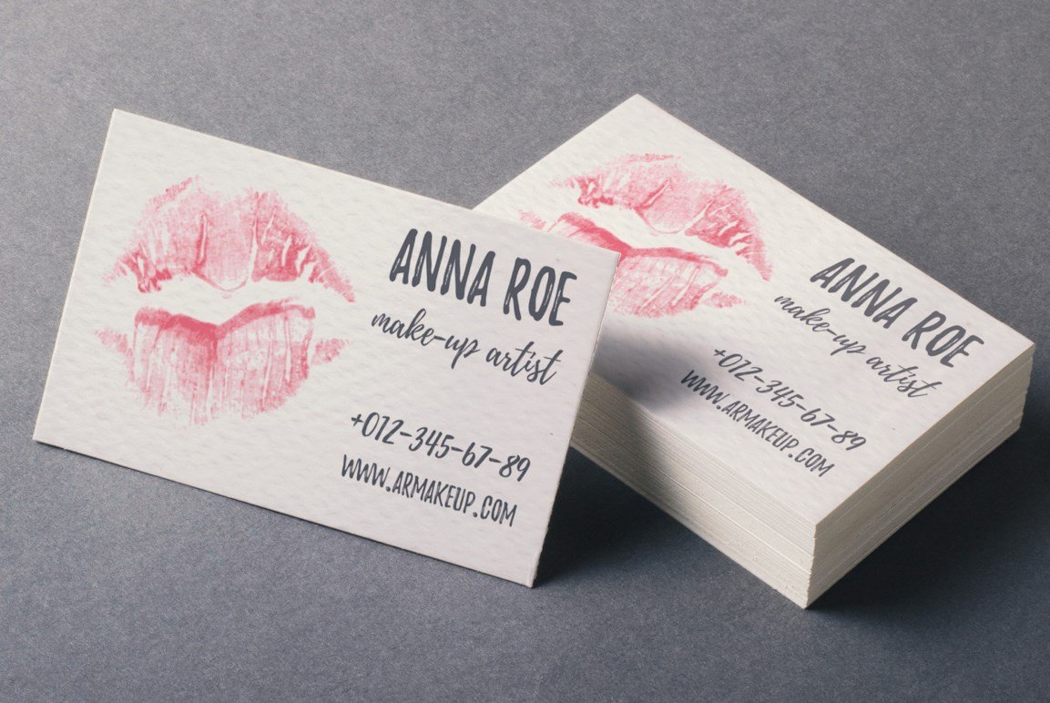 A lot of beige business cards with black letering and pink kisses