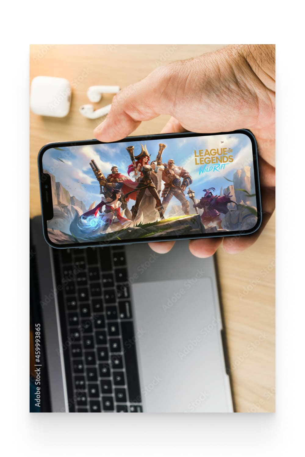 Male hand holding a smartphone with League of Legends mobile game app on the screen.