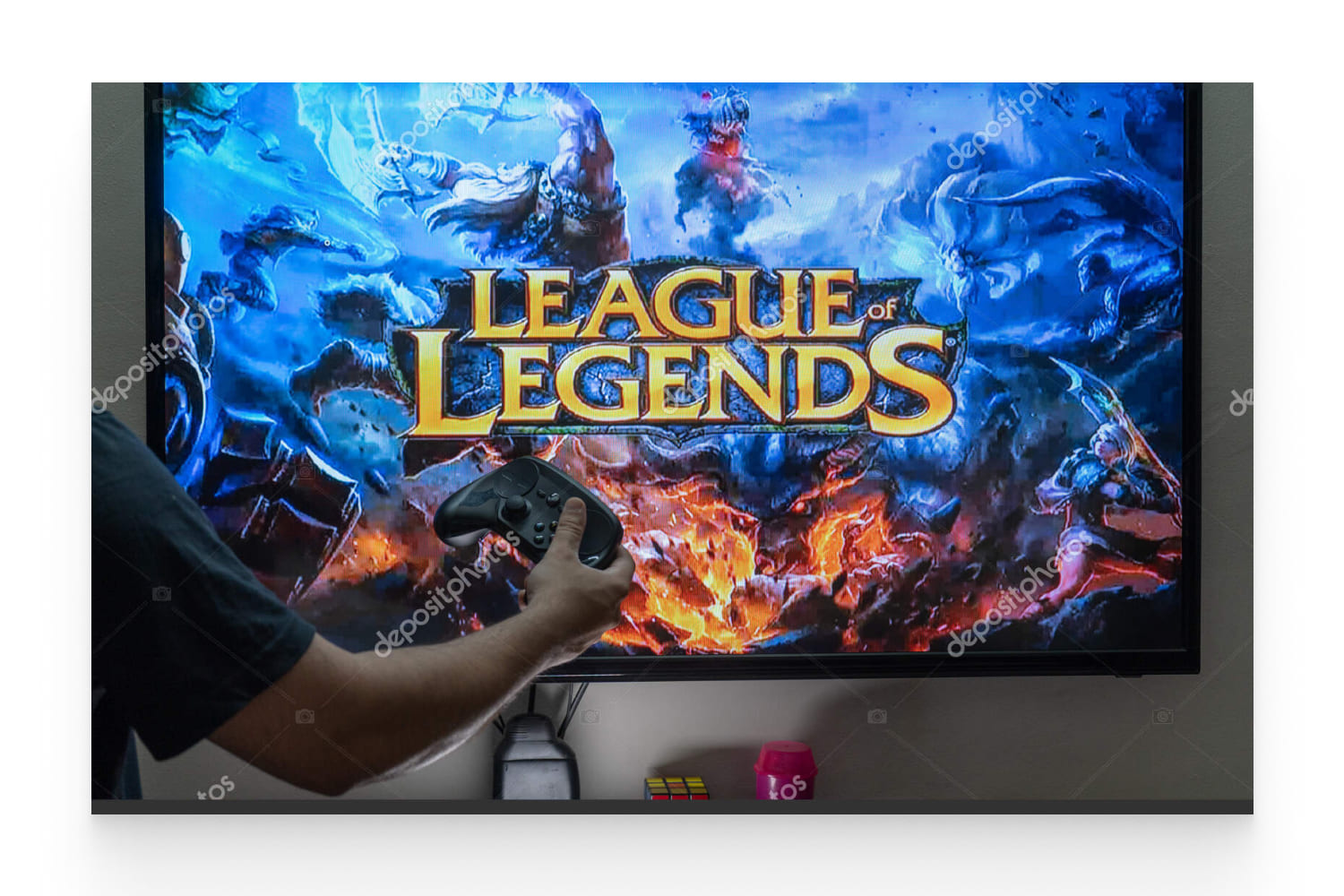 Man holding steam controller in front of a screen loading the league of legends.