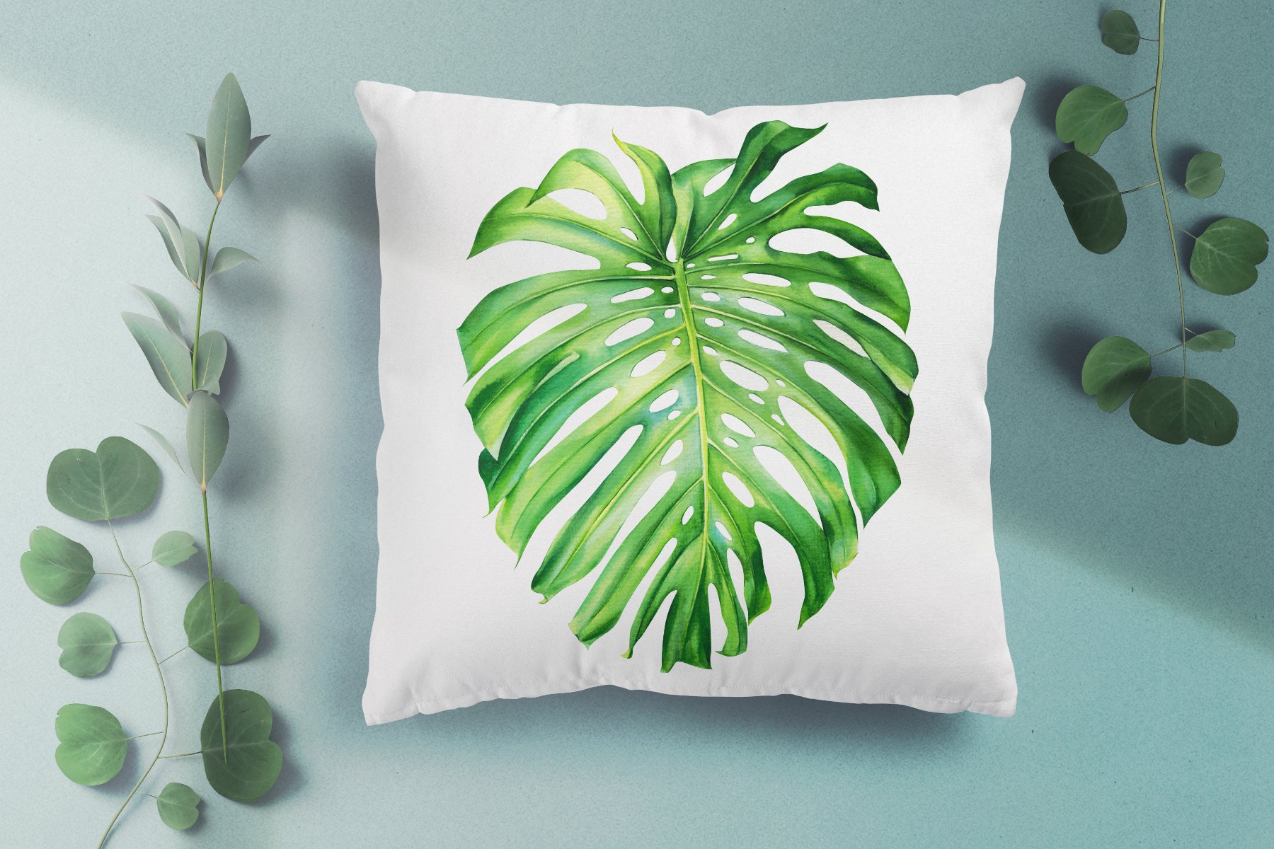 White pillow with a green leaf on it.