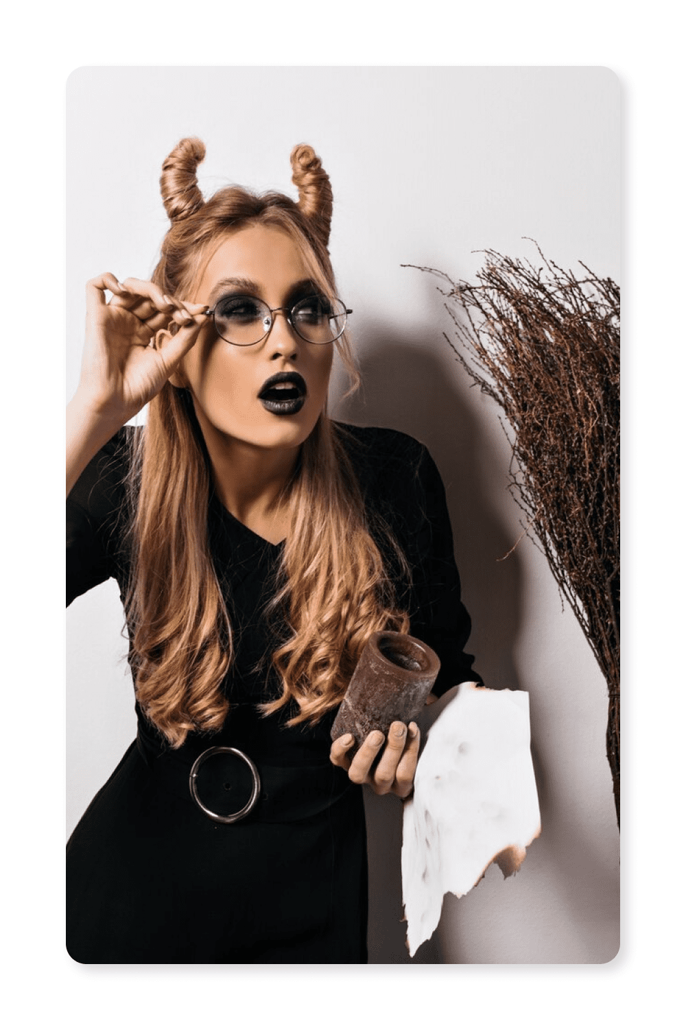 Photo of a girl in a black dress, glasses and horns from her hair.