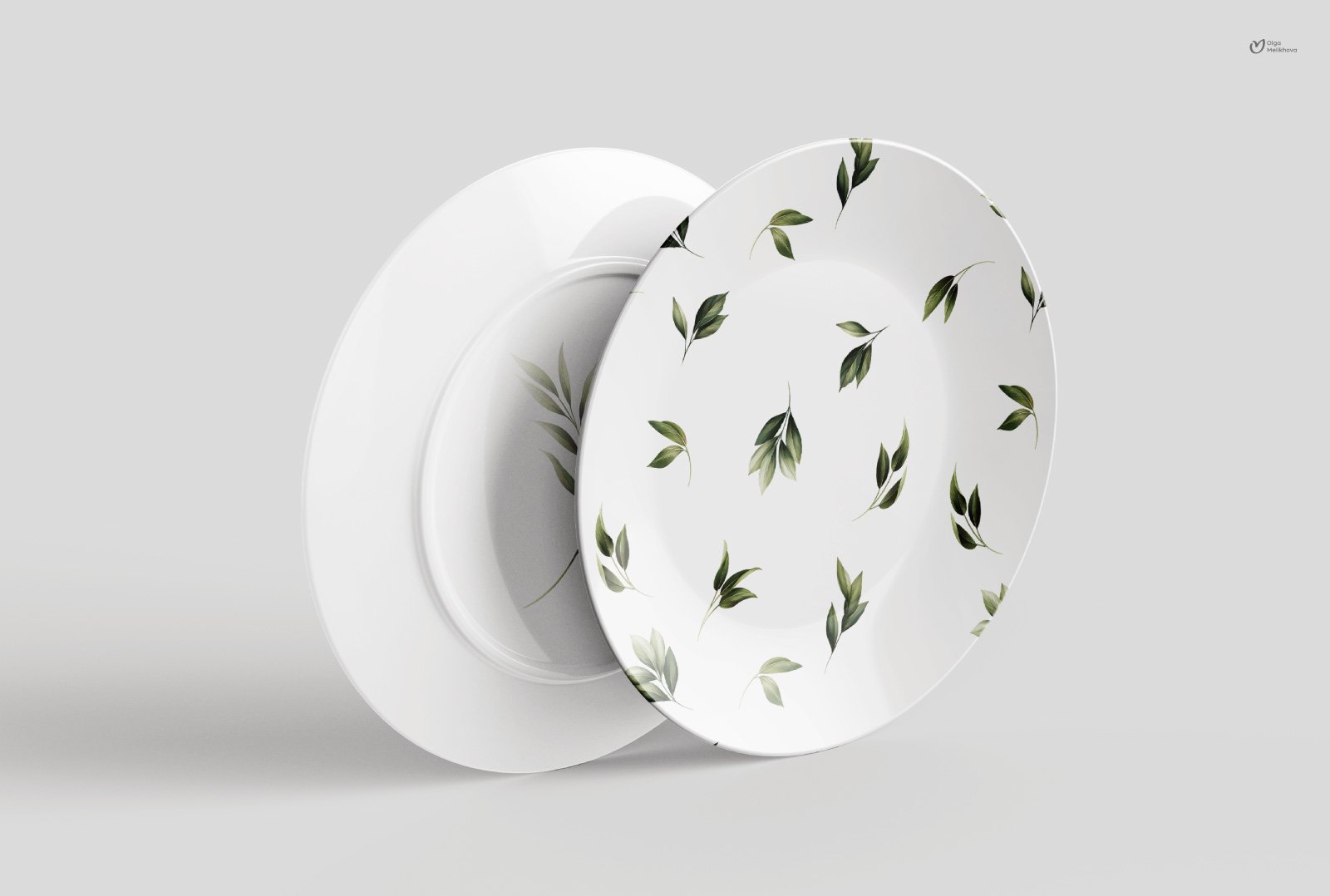 Two white plates with green leaves on them.