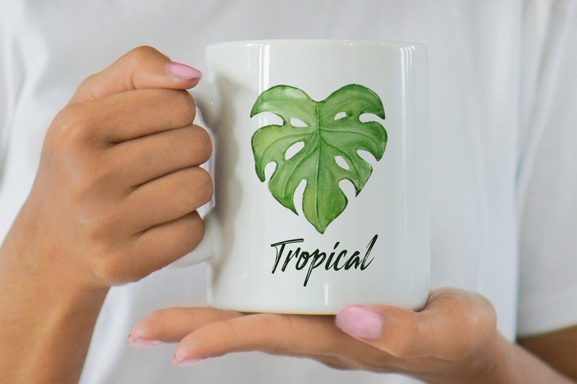 Woman holding a white coffee mug with a green leaf on it.