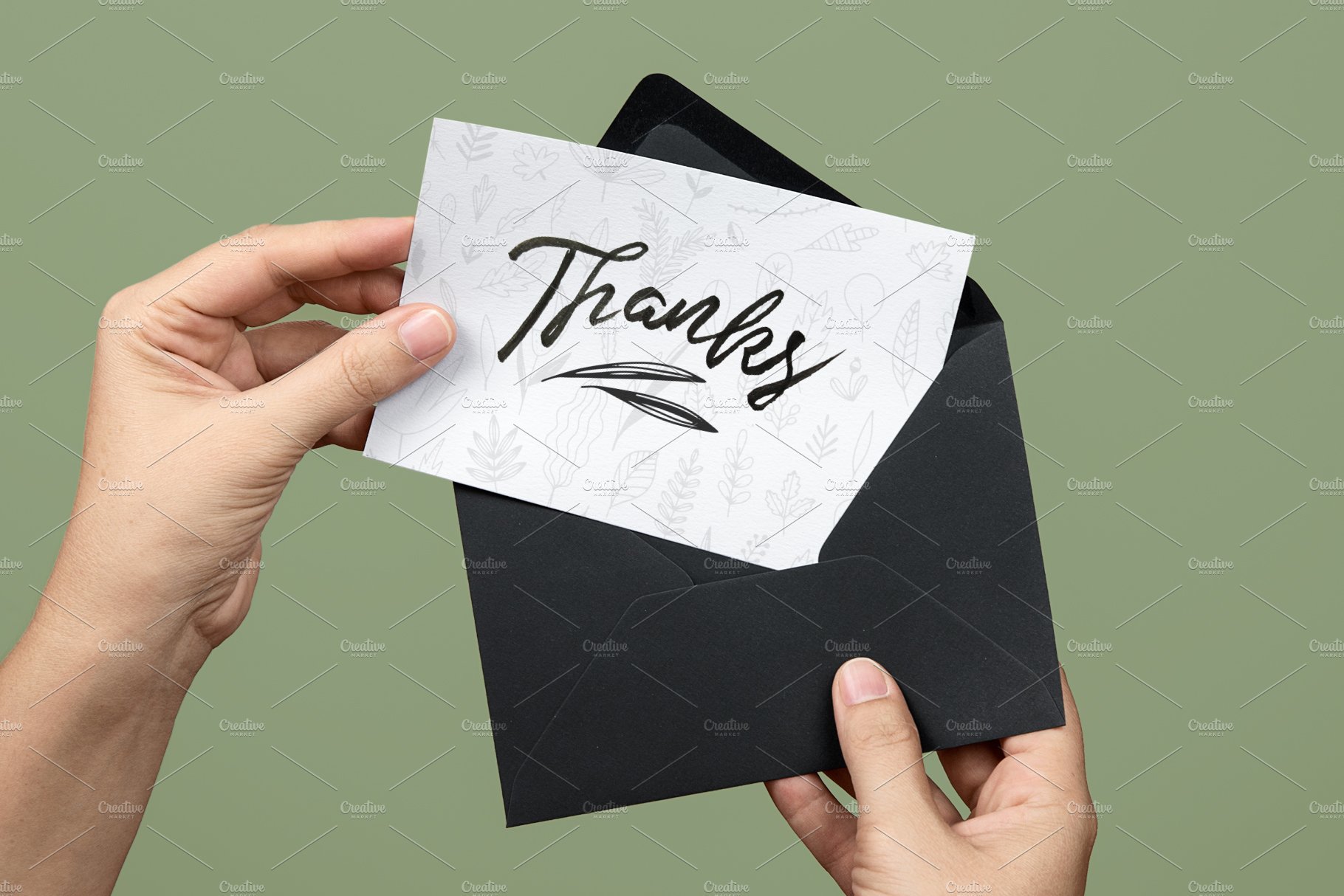 Hand holding a thank card with a black envelope.