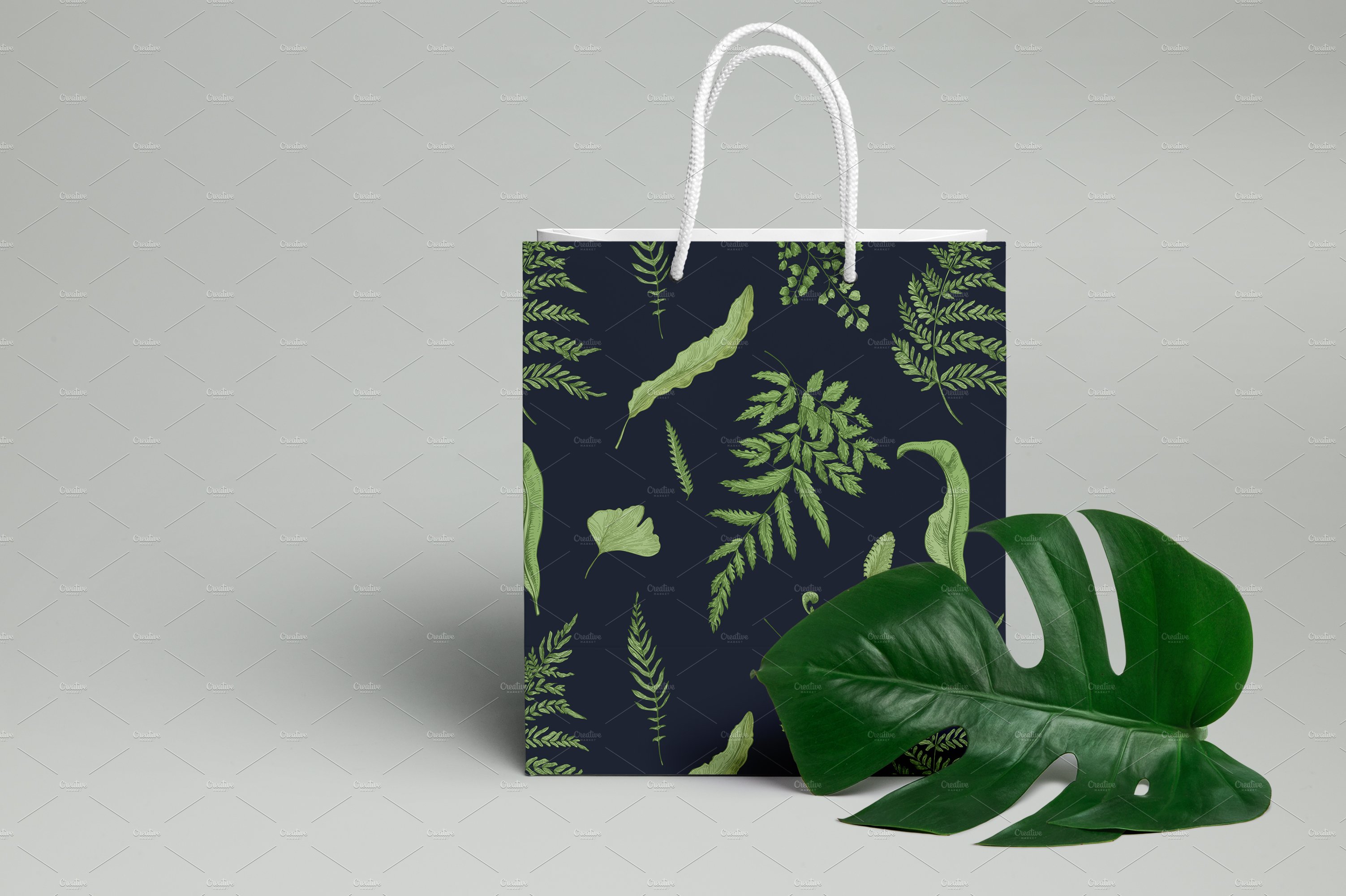 Paper bag with green leaves on a grey background.