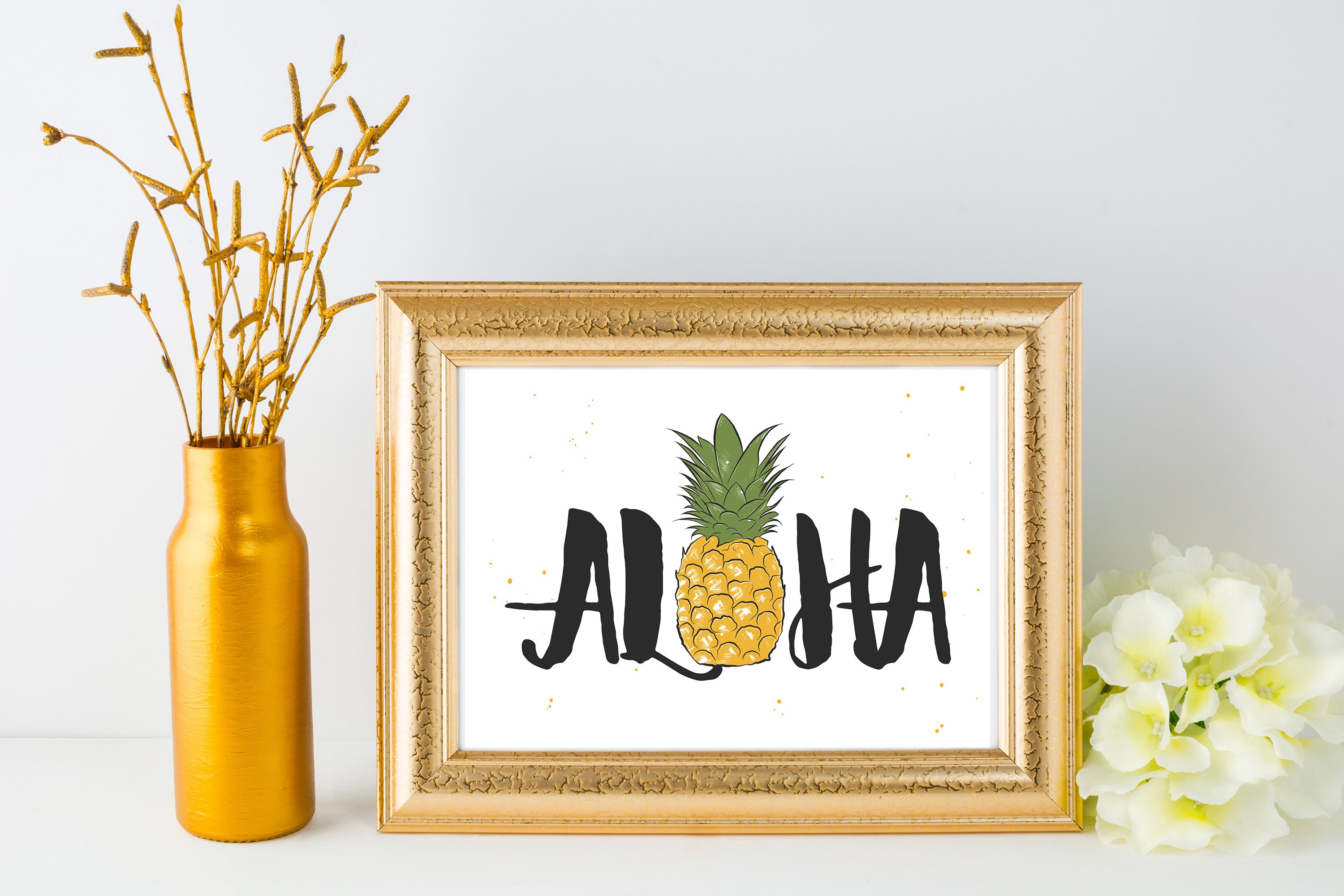 Picture of a pineapple in a frame next to a vase with flowers.