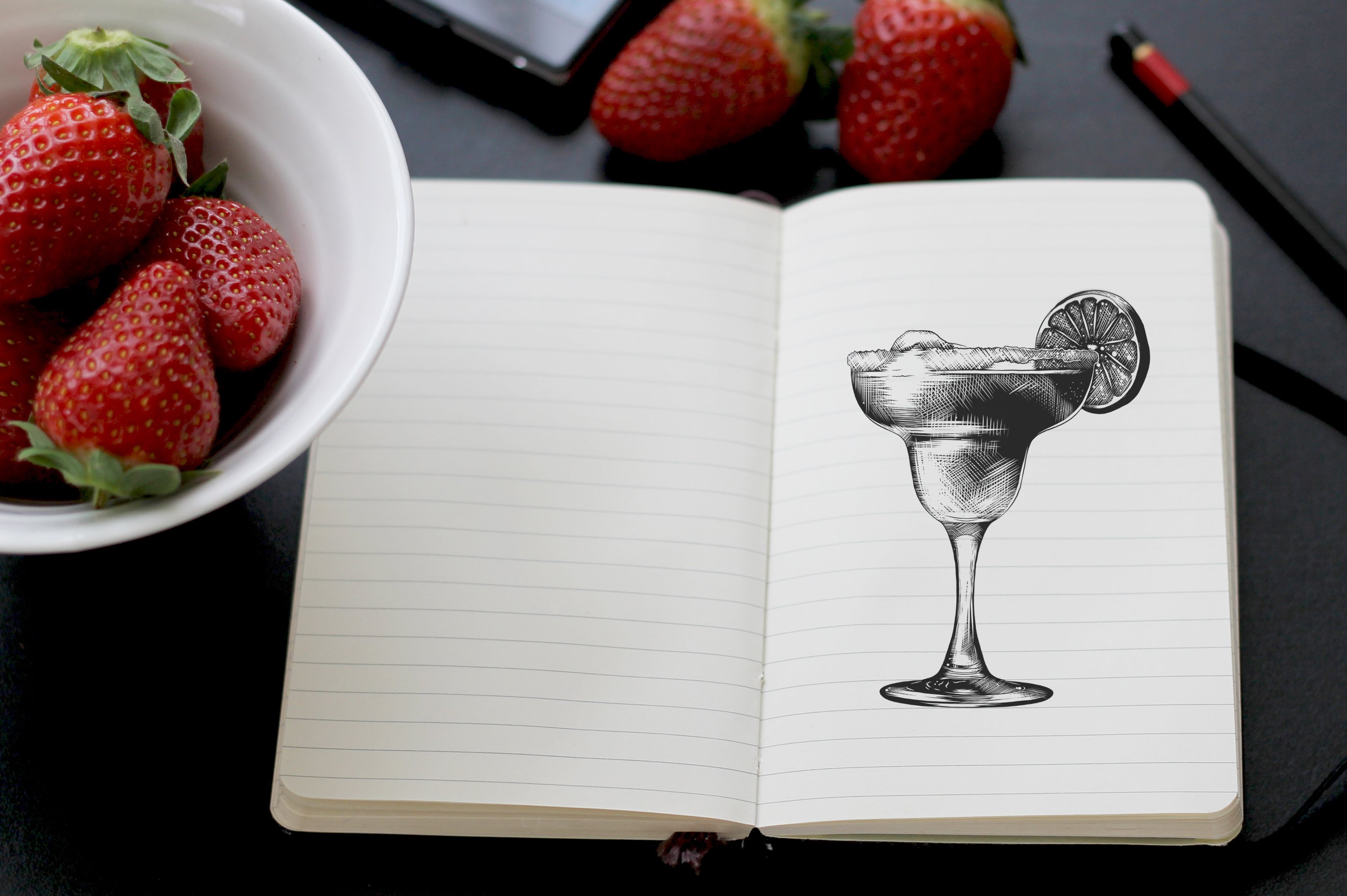 A notebook with a drawing of a cocktail and strawberries.