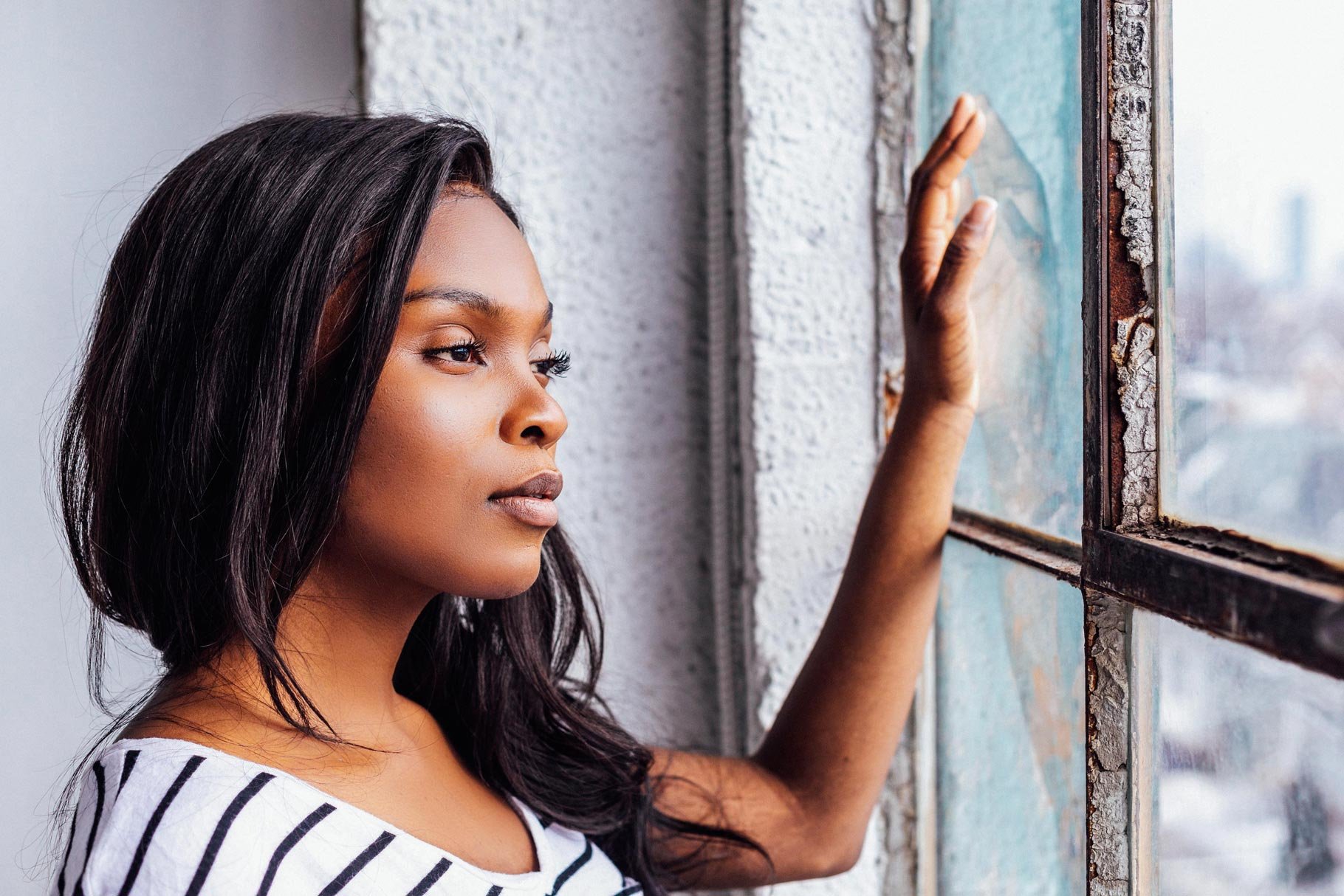 young woman gazes out of a rustic window 760