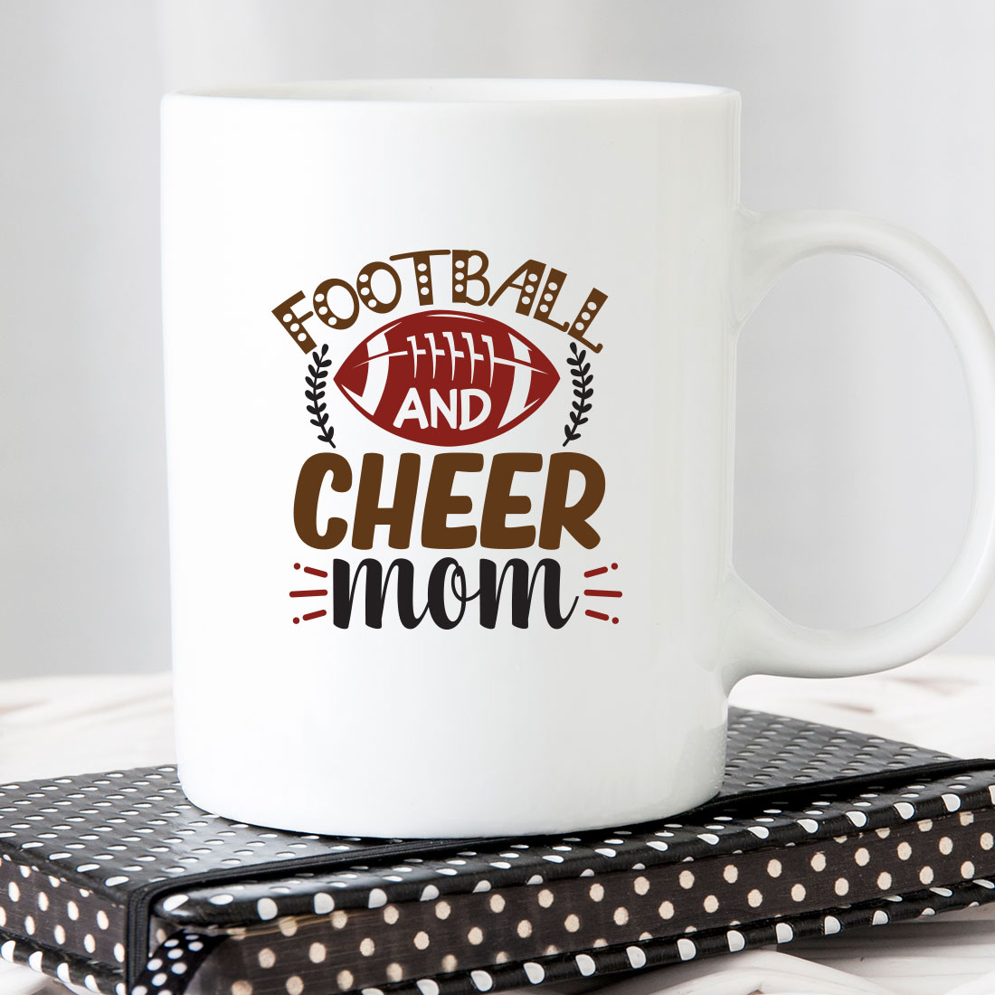 White coffee mug with a football and cheer mom on it.