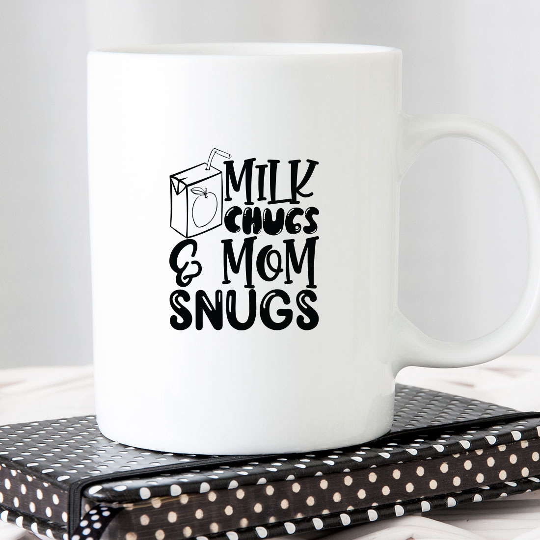 White coffee mug with the words milk chugs and mom snugs on.