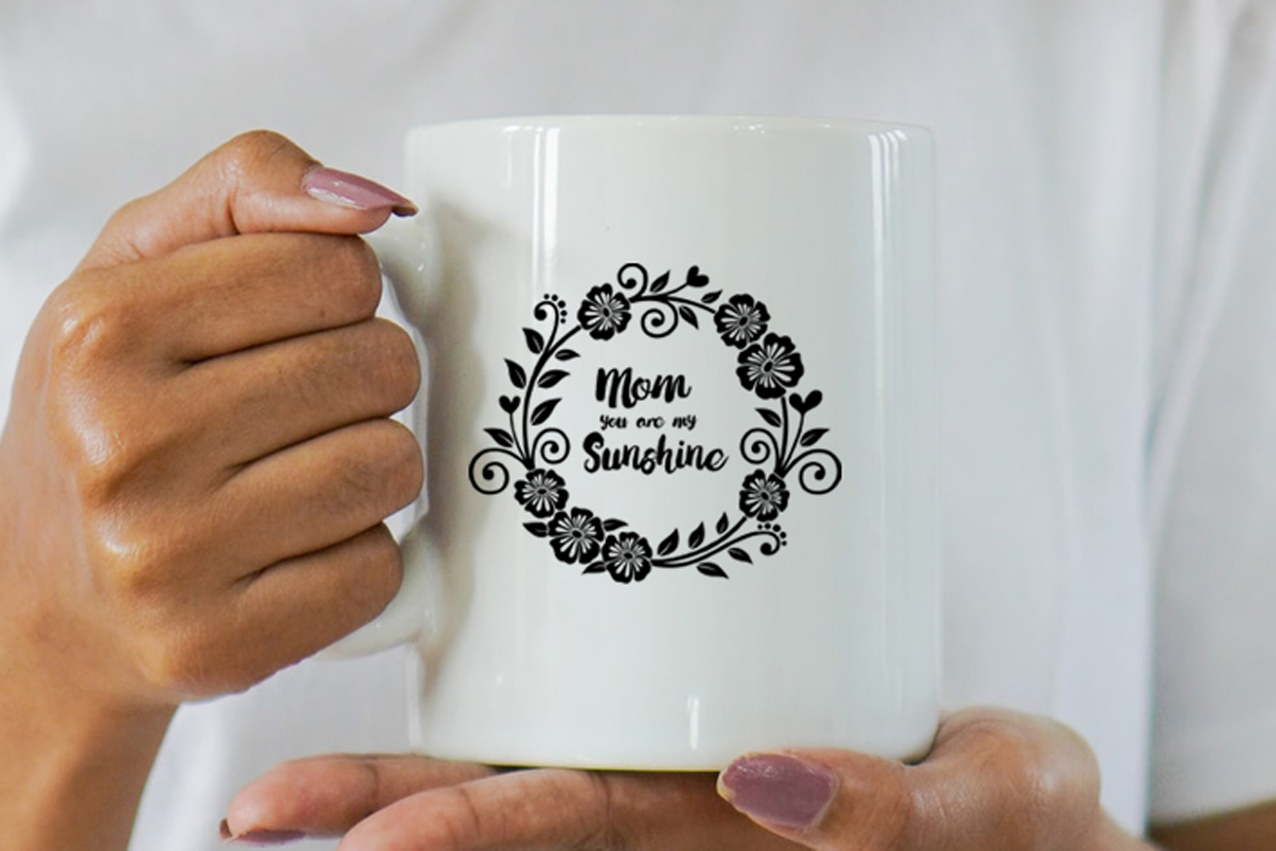 Woman holding a coffee mug with the words mom sunshine on it.